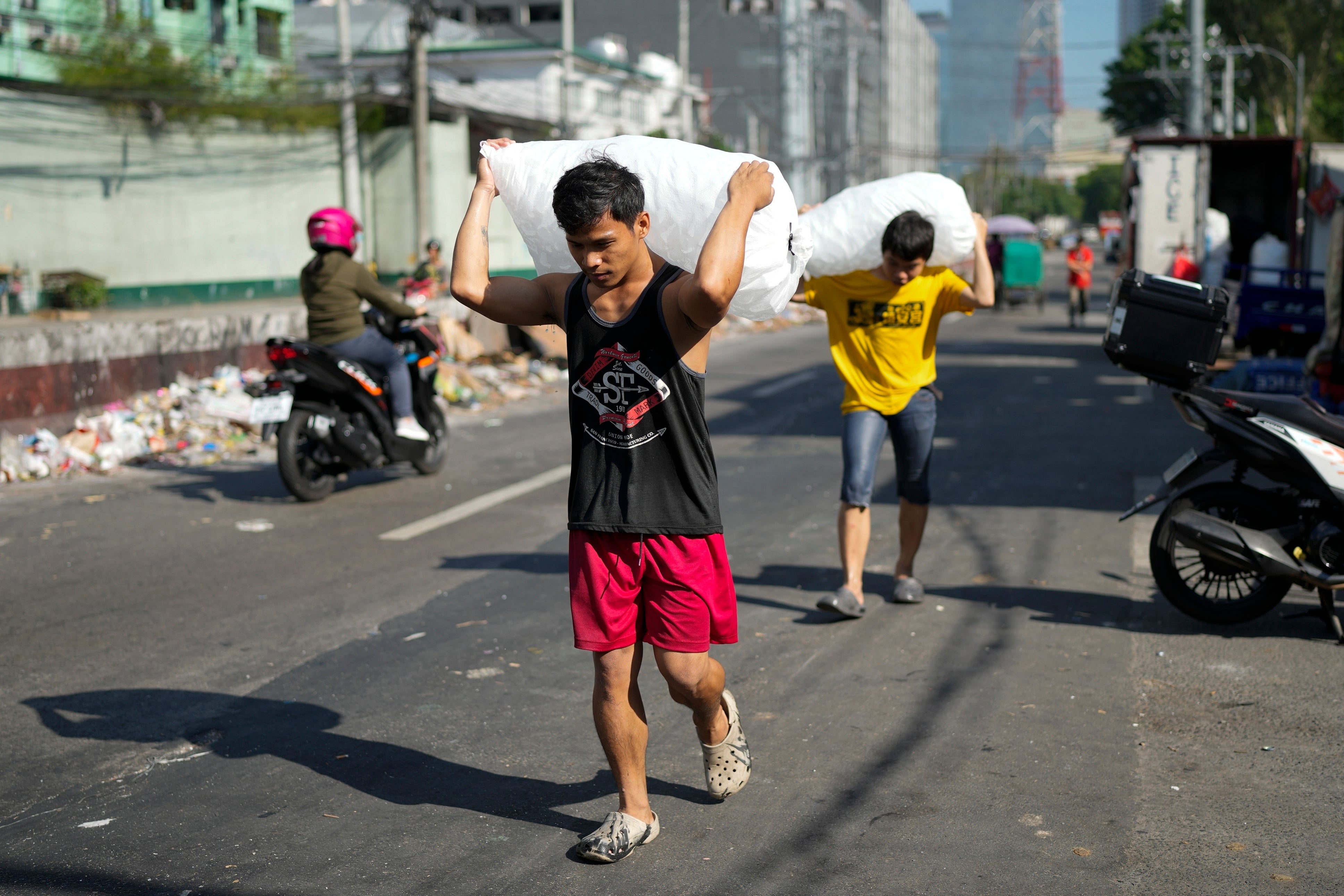Men deliver sacks of ice cubes as hot temperatures persist in Quezon city, Philippines