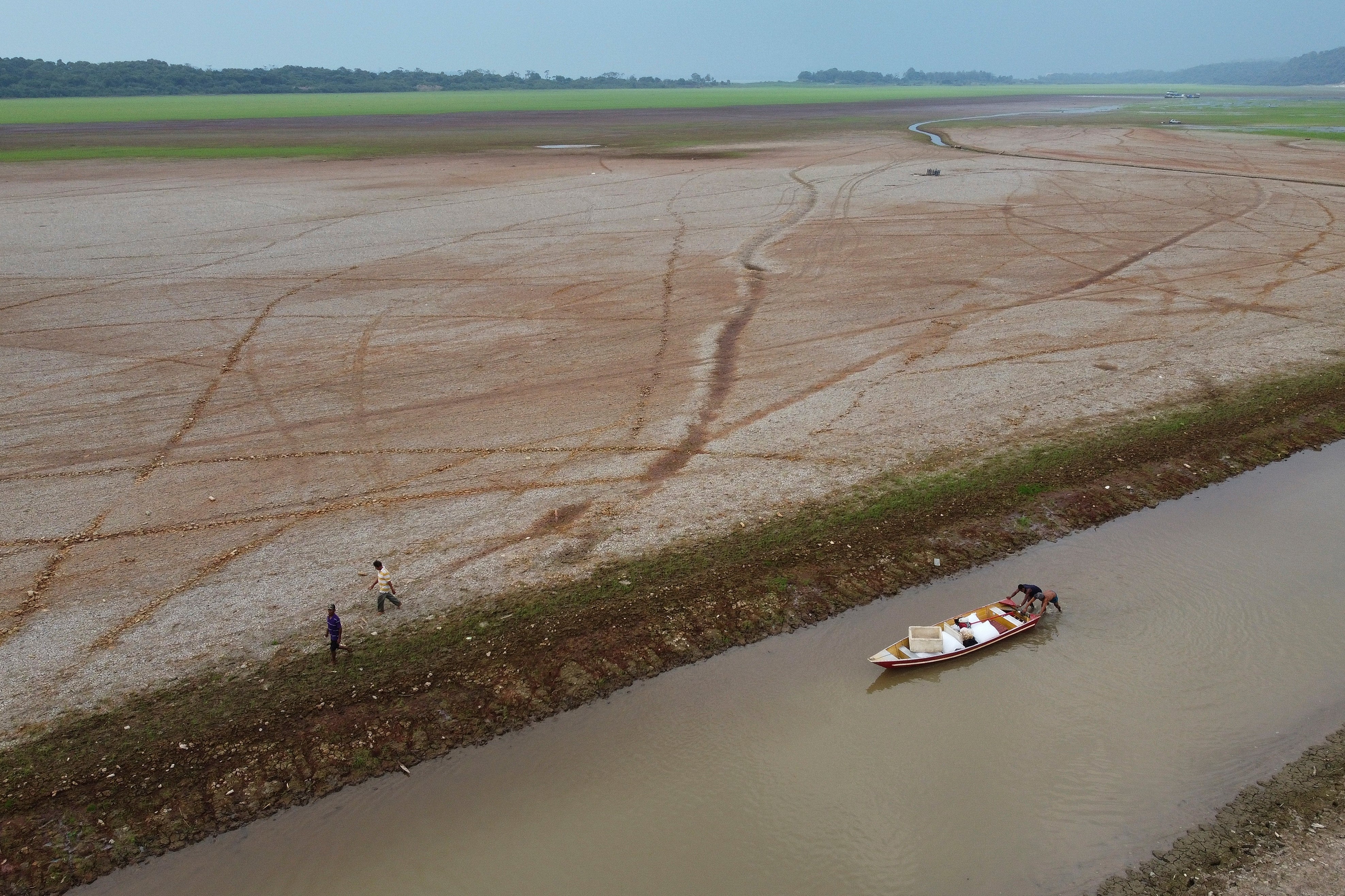 Fishermen push a boat in the Aleixo Lake amid a drought in Manaus, Amazonas state, Brazil, Sept. 24, 2024.