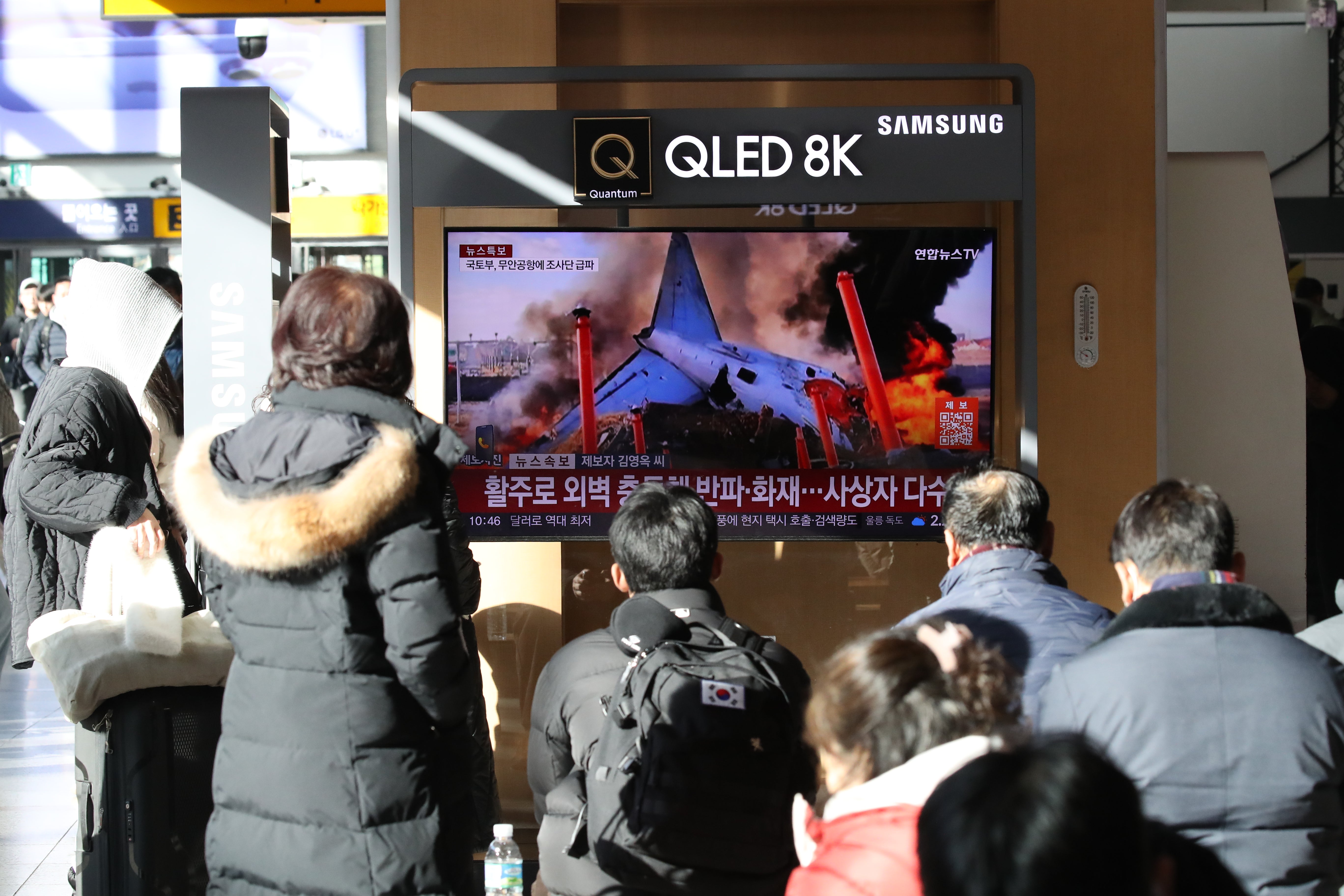 People watch the news regarding the plane crash, at Seoul station