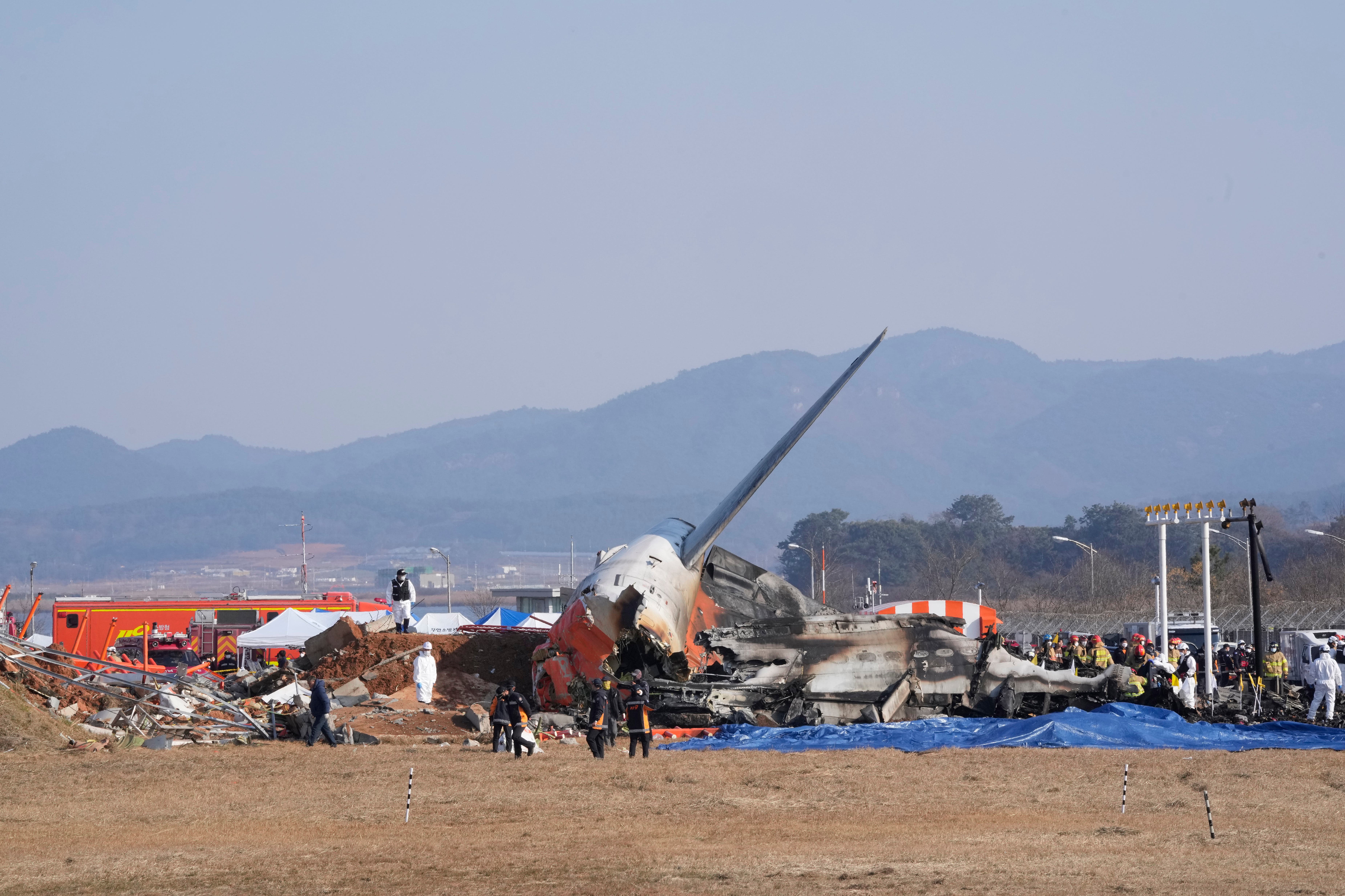 Firefighters and rescue team members work near the wreckage of the passenger plane at Muan International Airport (Ahn Young-joon/AP/PA)