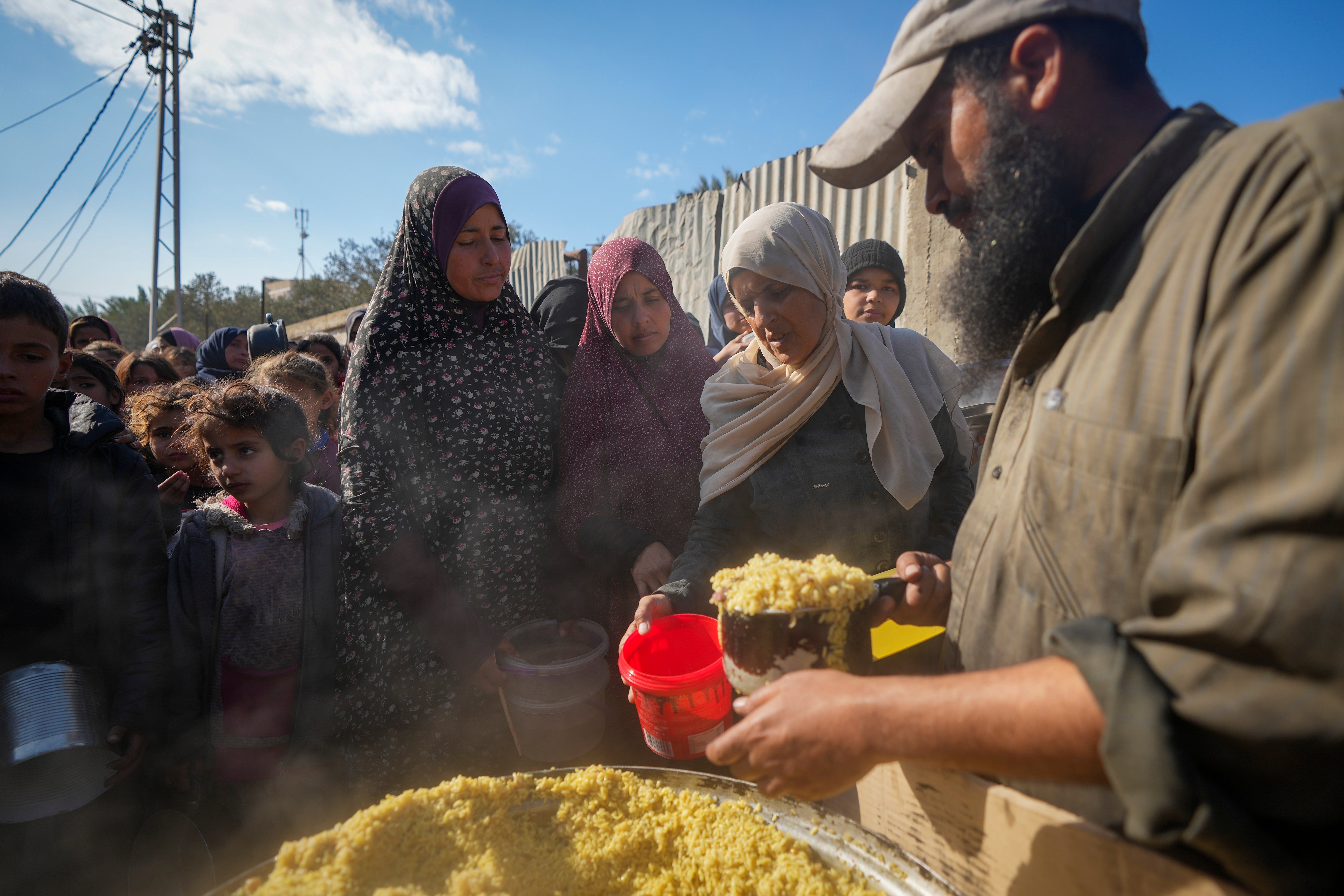 Palestinians receive donated food at a distribution centre in Deir al-Balah, Gaza