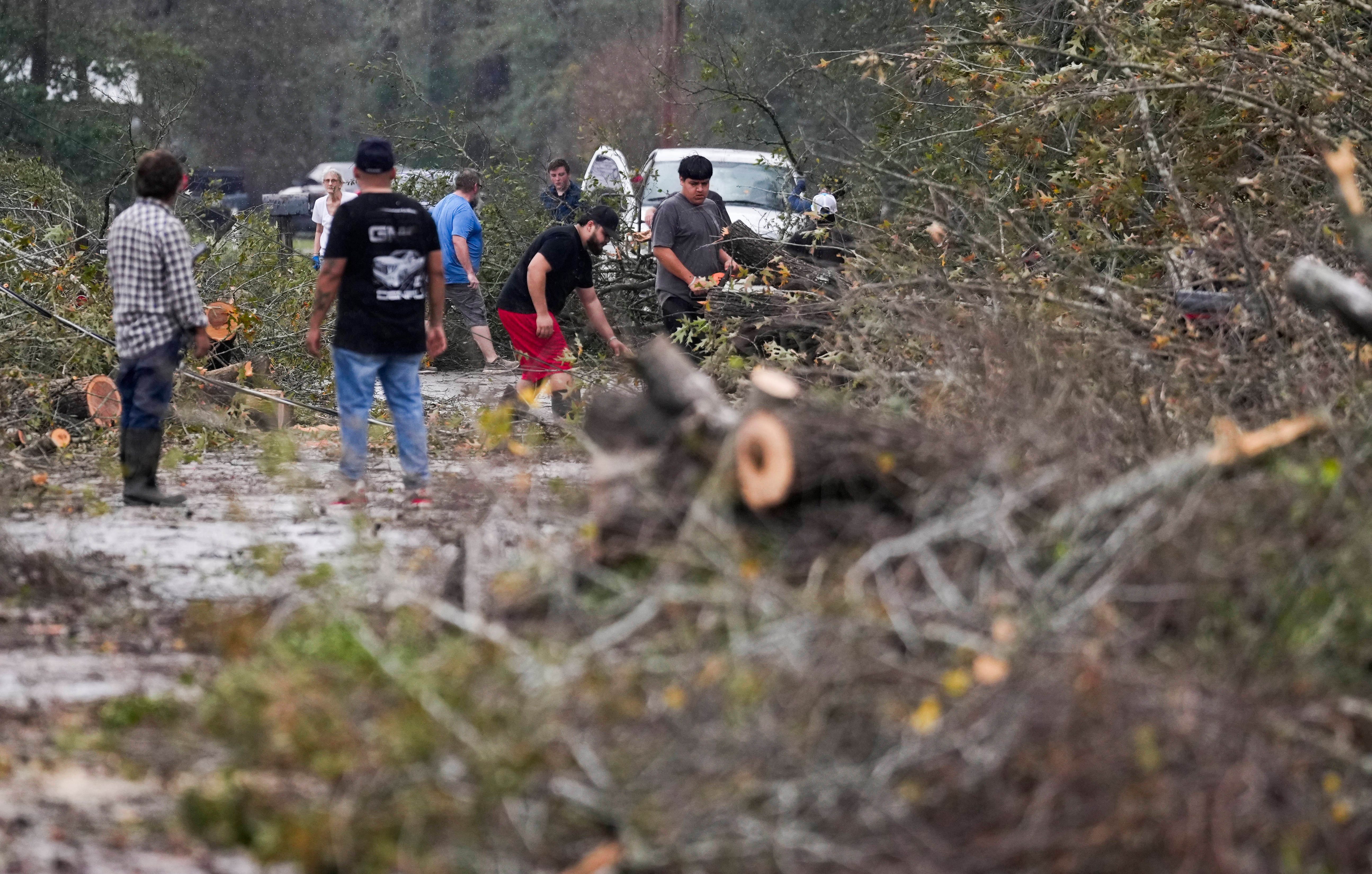 People clear a street after trees fell following storms near Houston, Texas, on Saturday. The severe weather brought deadly tornadoes to the Lone Star State and other parts of the South