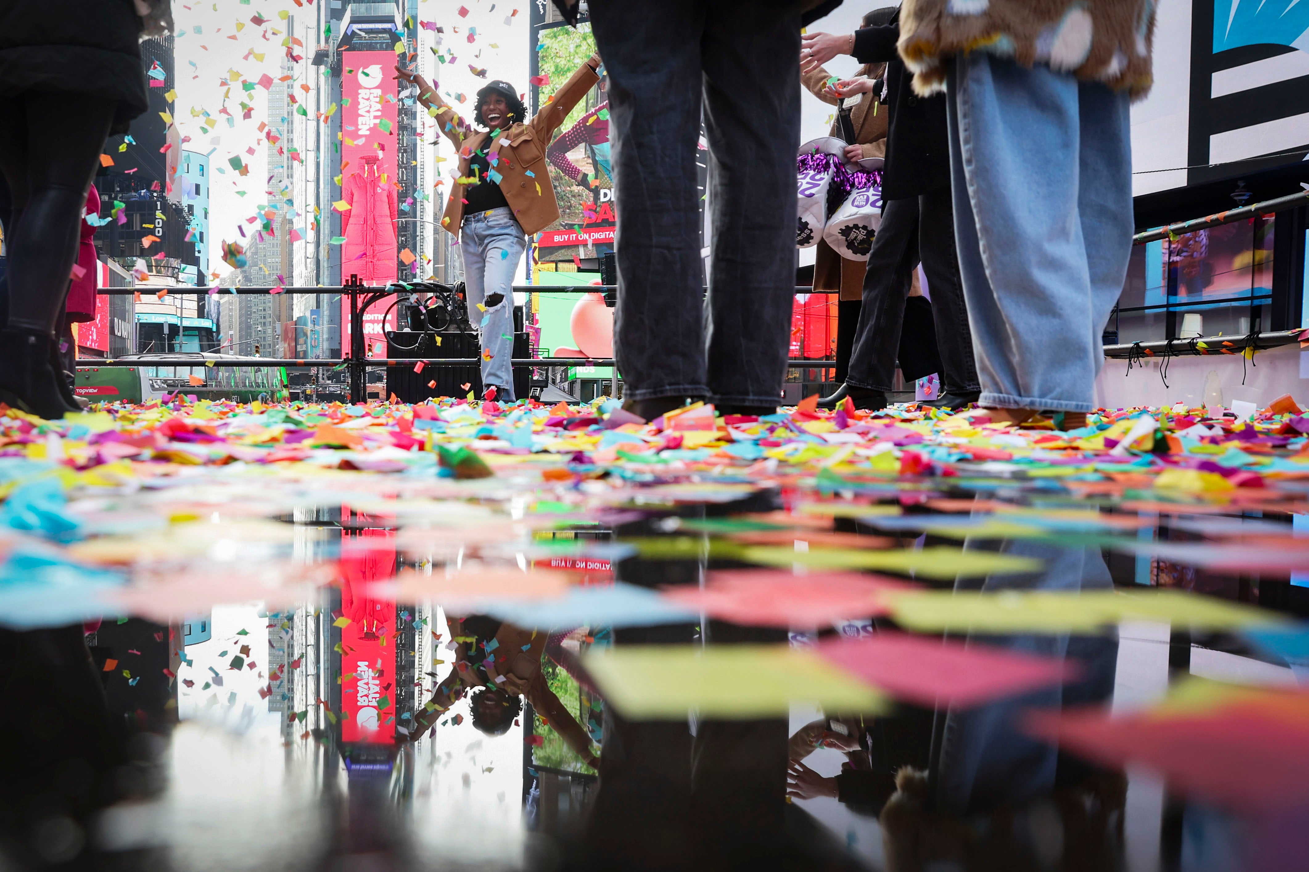 People pose for photos as they throw confetti ahead of New Year’s Eve on Sunday in New York City’s Times Square. One million visitors are expected to mark the holiday there