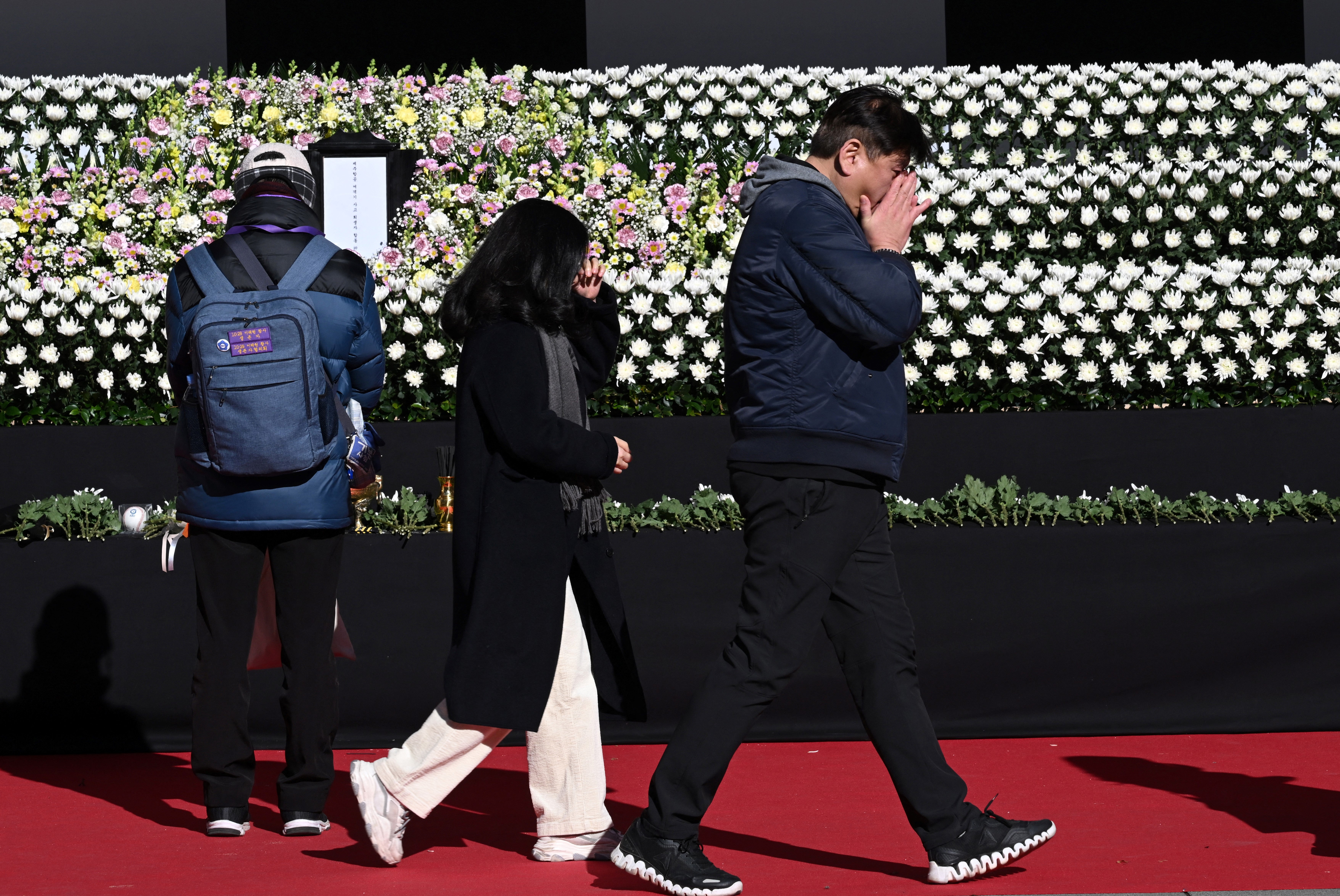 Mourners react as they pay their respects at a memorial altar for the victims of the Jeju Air plane crash