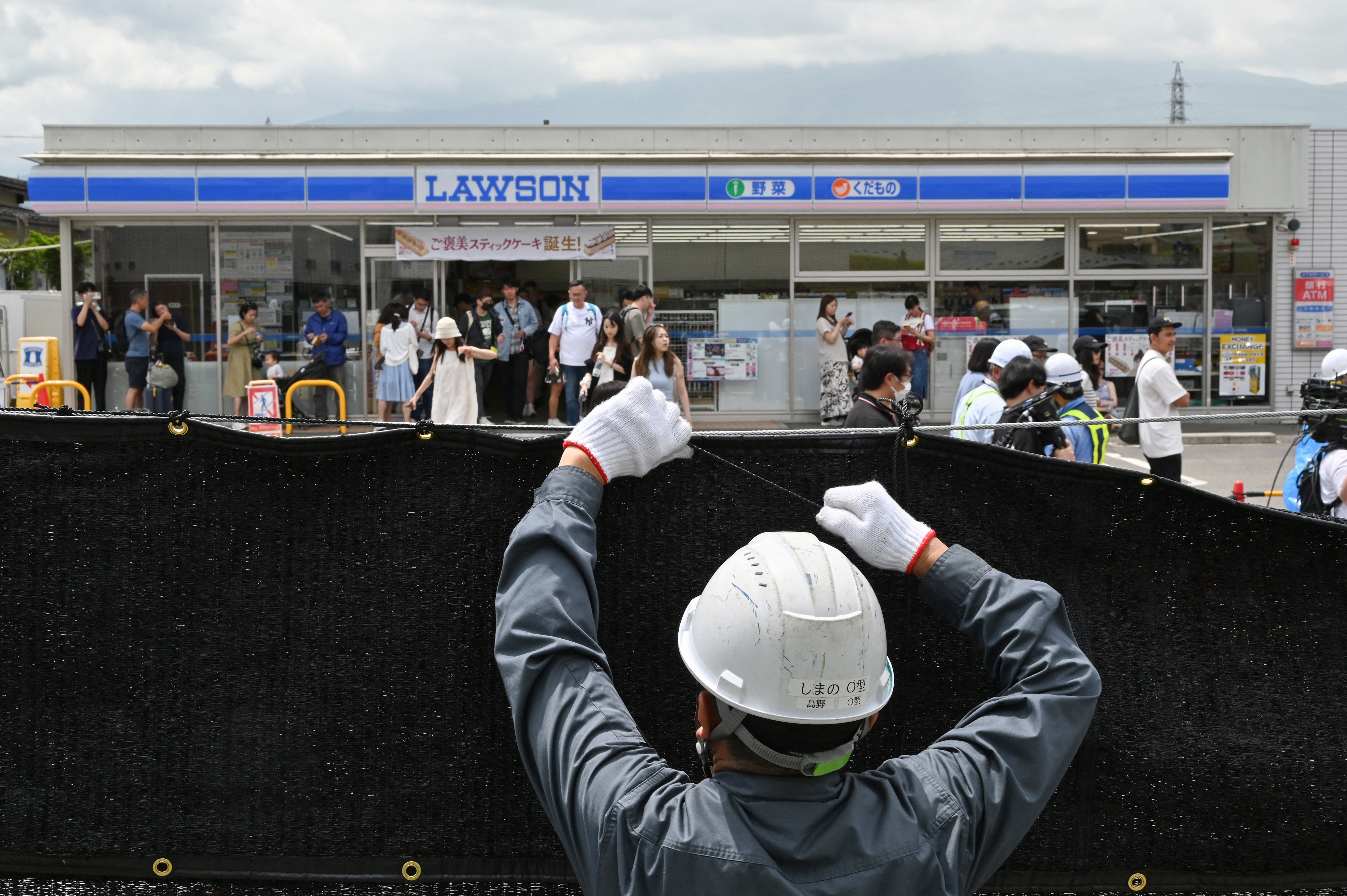 A worker installs a barrier to block the sight of Japan’s Mount Fuji emerging from behind a convenience store to deter badly behaved tourists in the town of Fujikawaguchiko