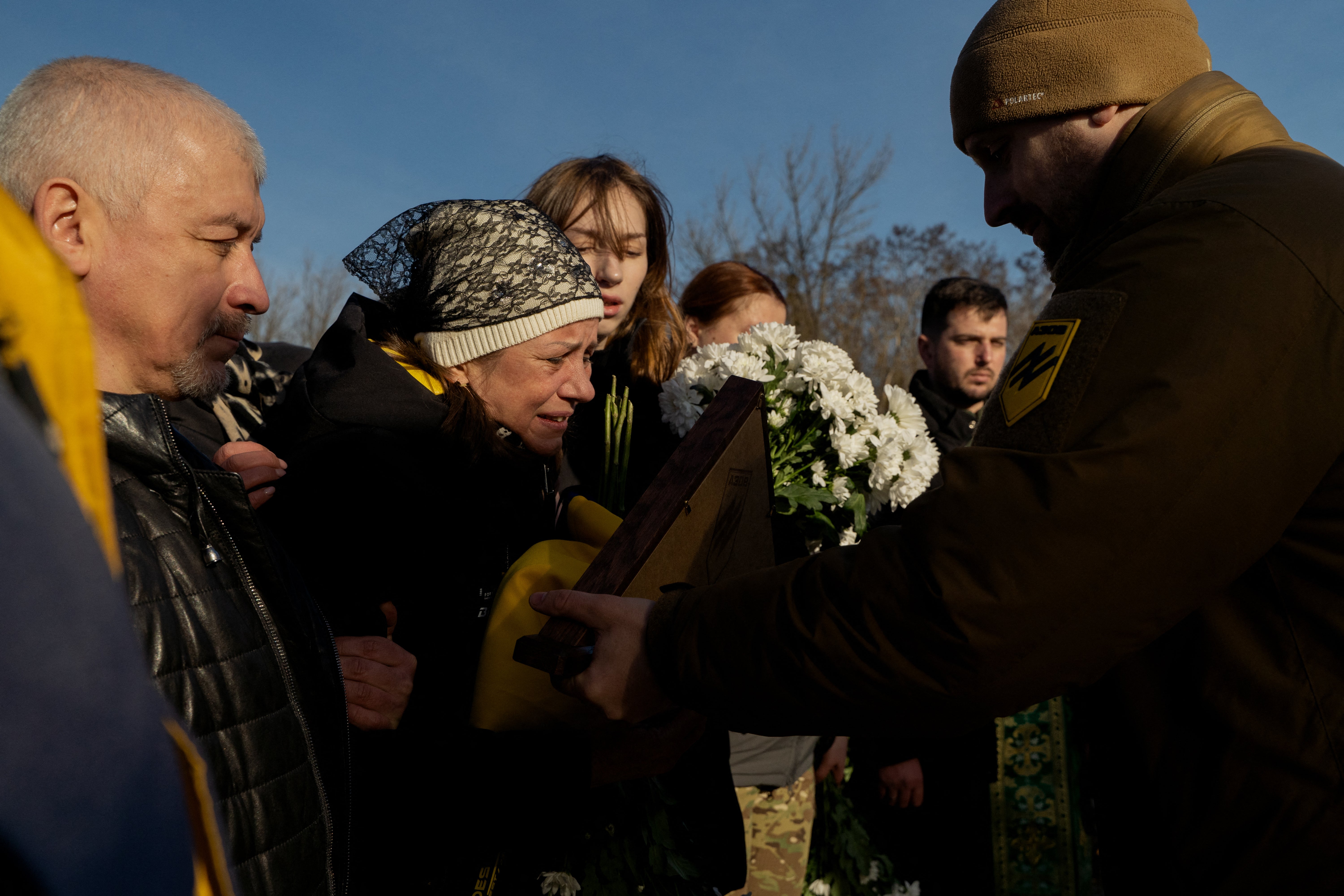 A soldier passes a flag to mother of late Ukrainian serviceman Danylo Bobrykov, callsign ‘Harvey’