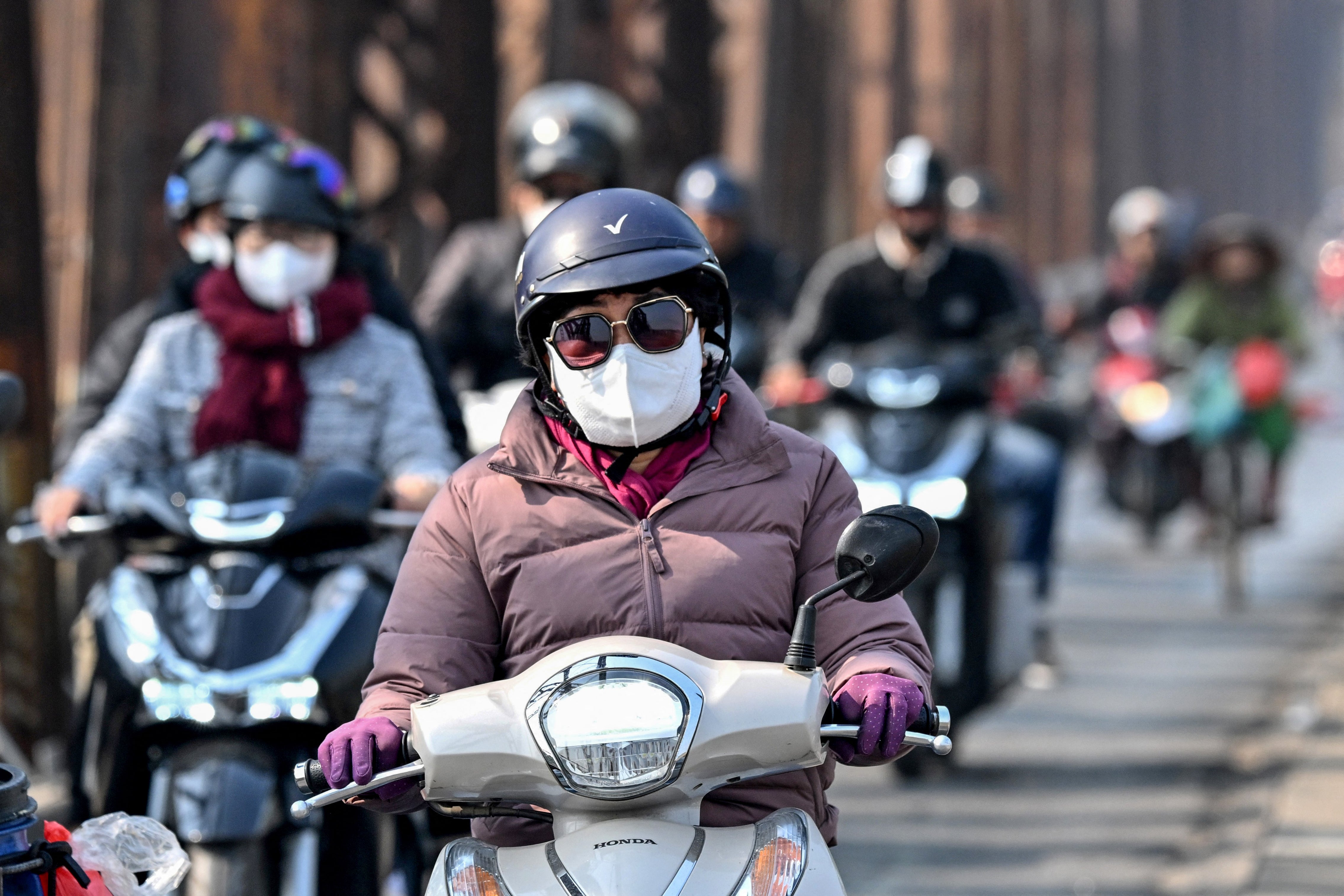 A motorist wearing a face mask rides a scooter on Long Bien Bridge amid heavy air pollution conditions in Hanoi on January 3, 2025