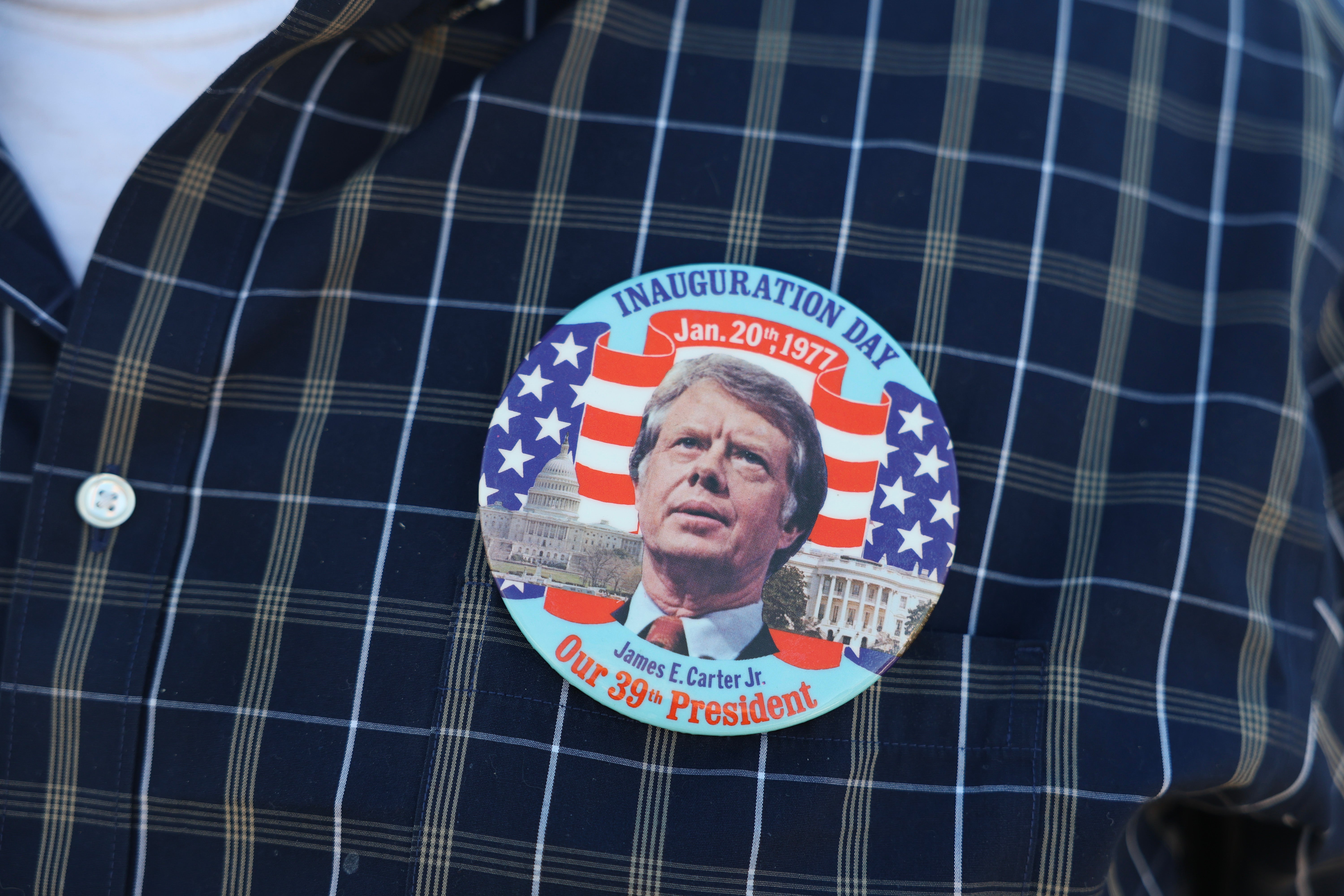 A mourner wears a Jimmy Carter inauguration button from 1977