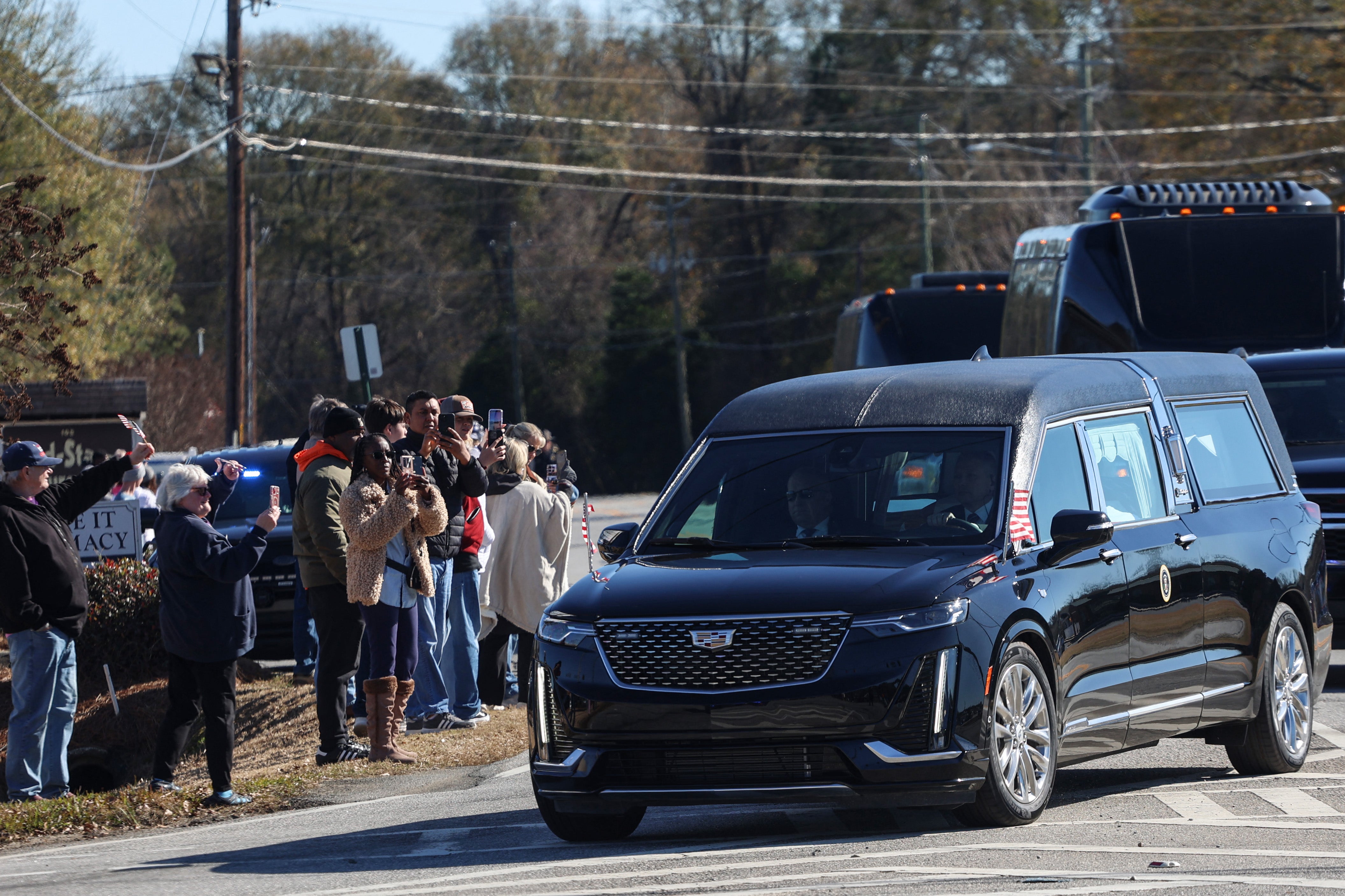 Mourners in Byron, Georgia watch as Jimmy Carter’s procession passes through on its way to Atlanta