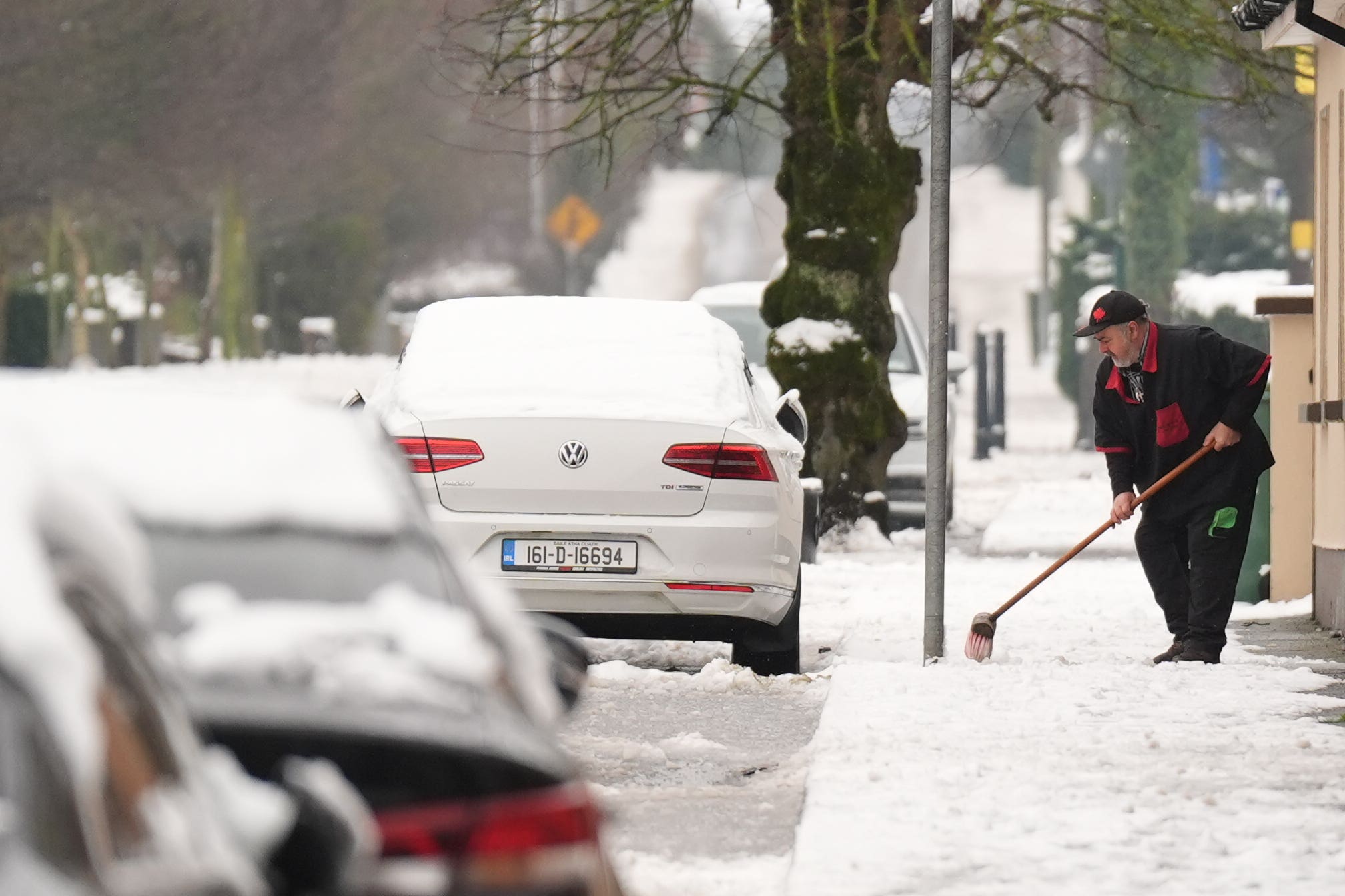 A man clears snow from the pavement in Ballylynan in County Laois, Ireland (Niall Carson/PA)