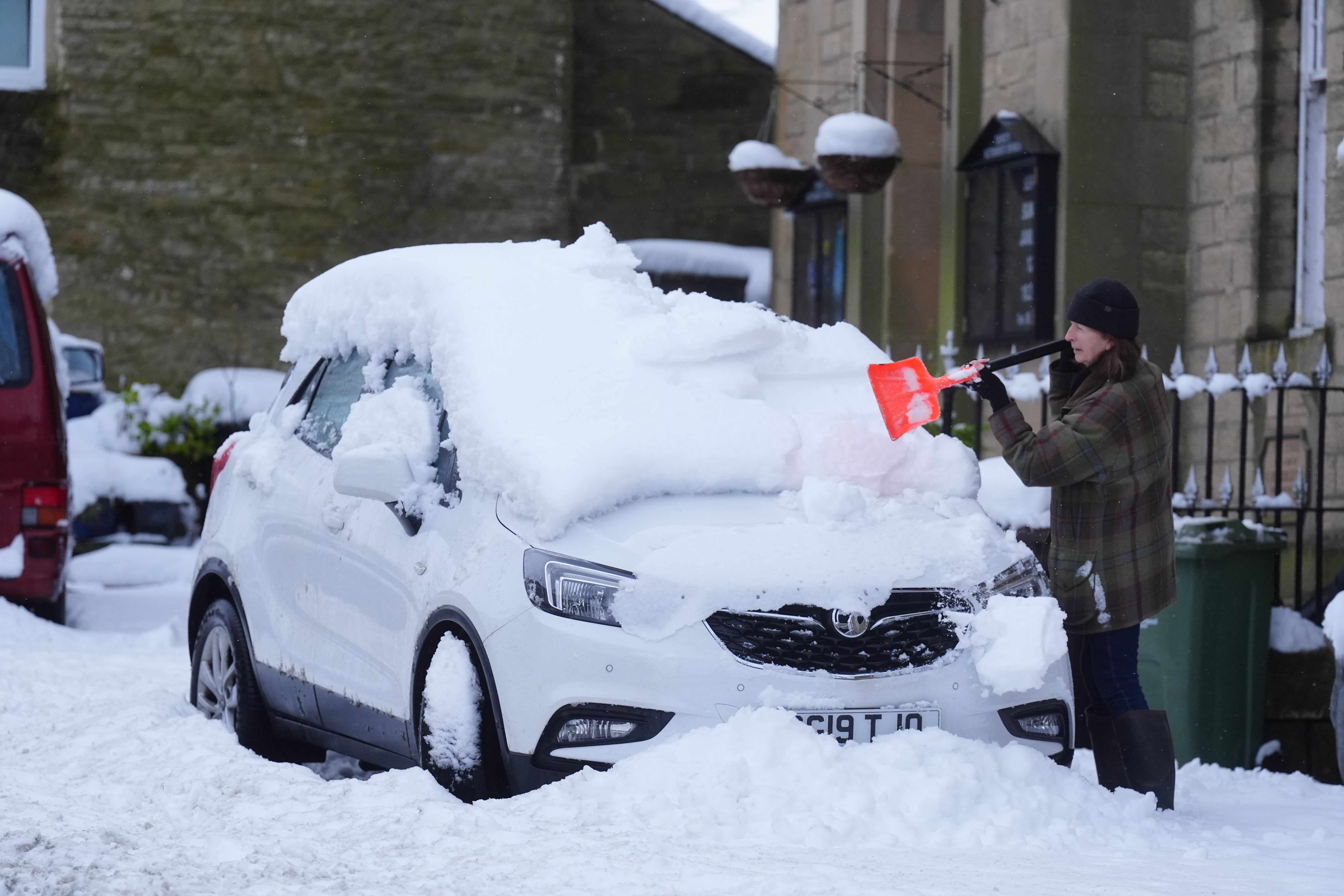 An individual removes snow from a vehicle in Allendale, Northumberland