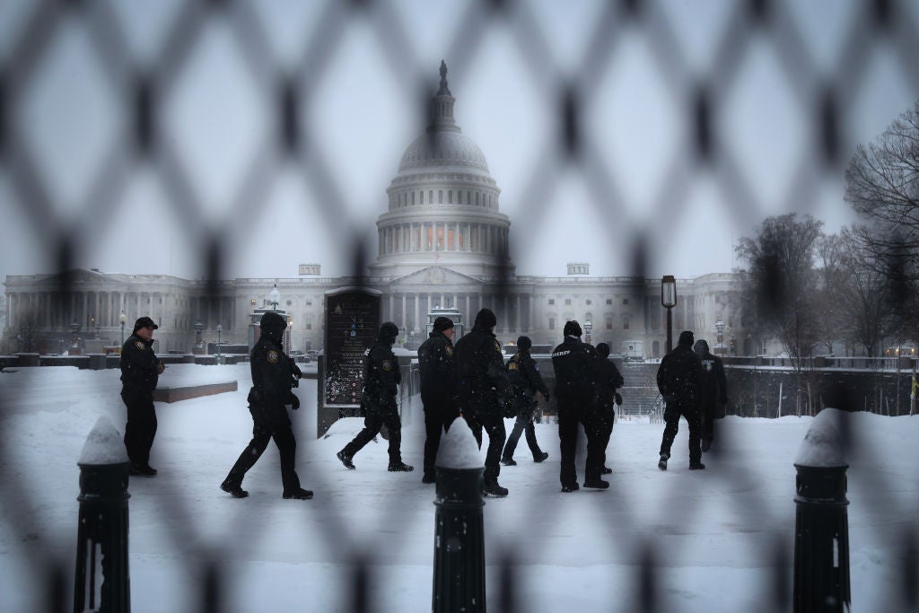 The snow-covered US Capitol building is seen through black security fencing on the fourth anniversary of the January 6 attack.