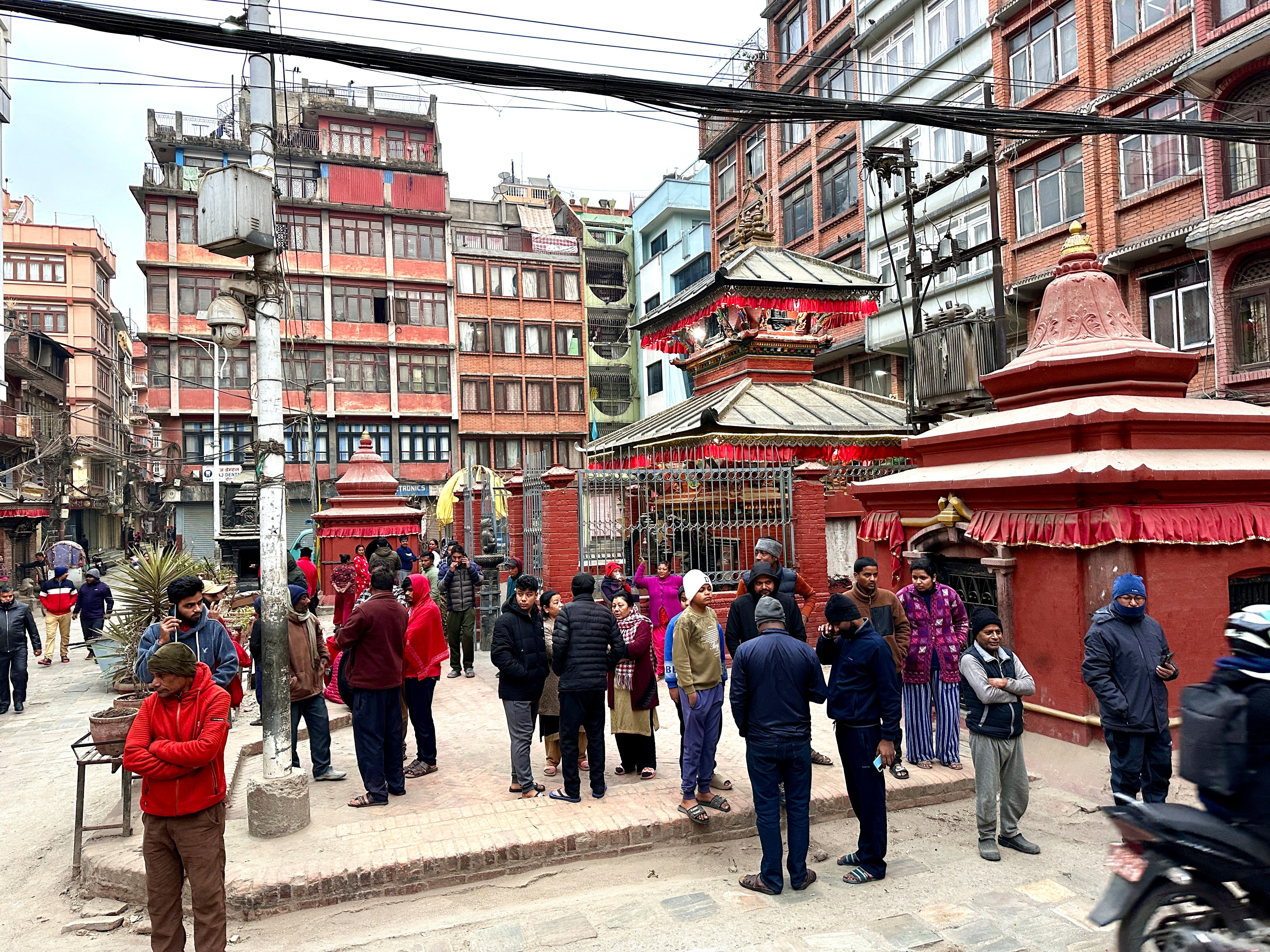 Nepalese people stand after rushing out of their homes after experiencing an earthquake in Kathmandu