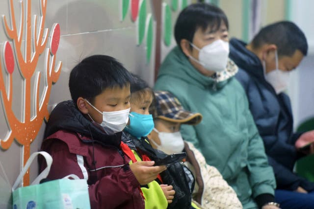 <p>Masked children, accompanied by adults, wait to be seen by medical staff at the pediatric department of a hospital in China amid a HMPV outbreak </p>