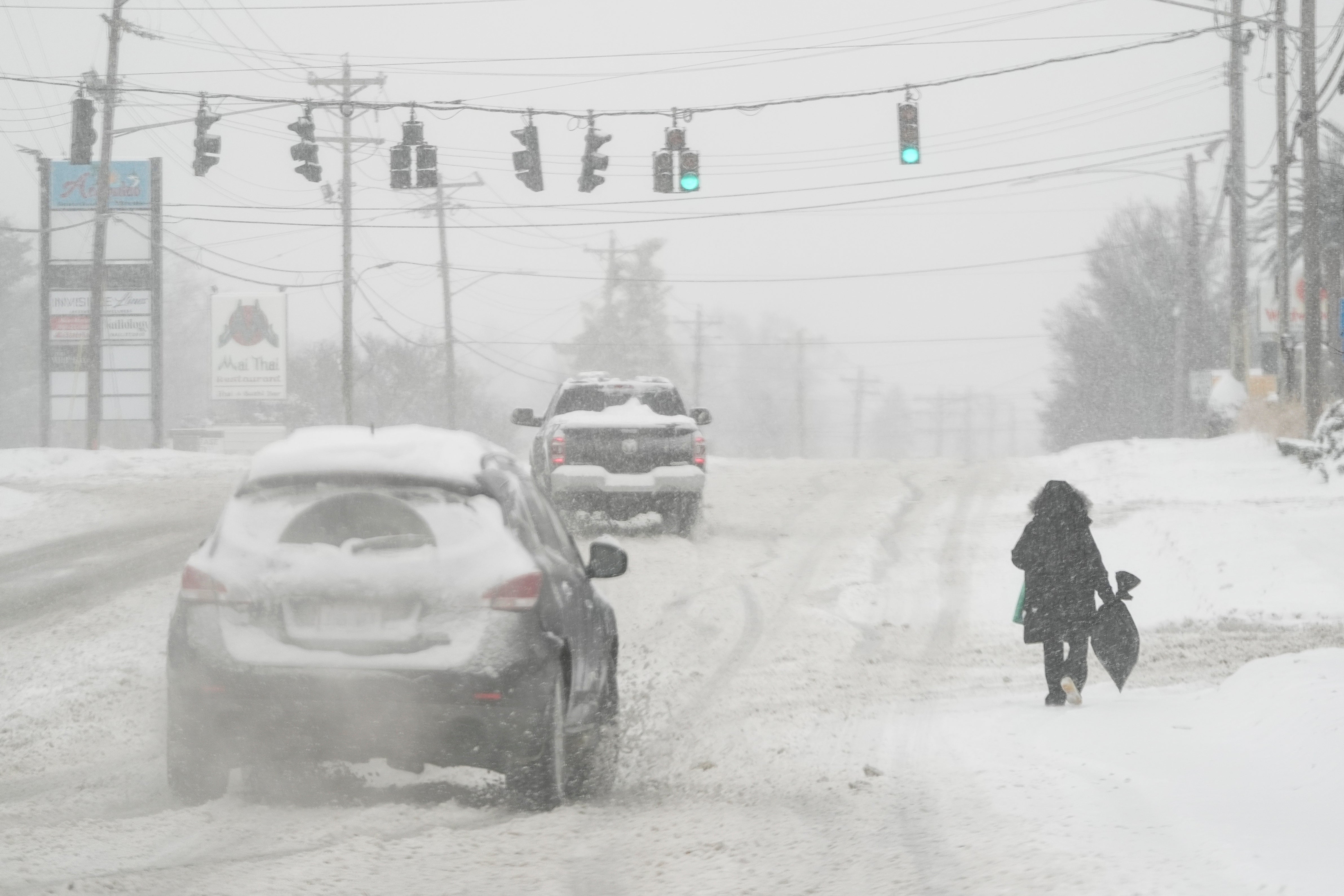 Heavy snow falls as a person walks along U.S. Route 42 in Florence, Ky., Monday, Jan.