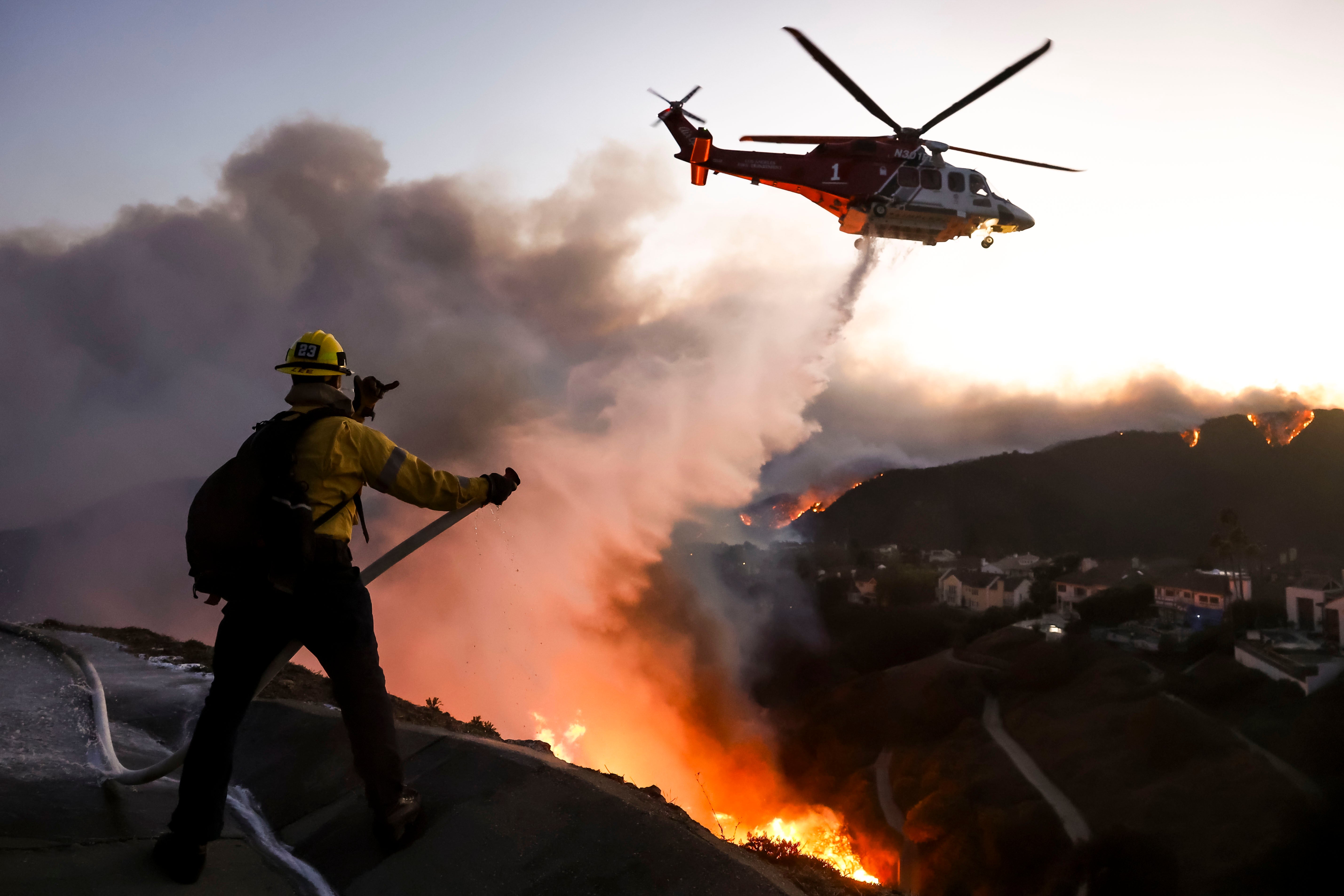 Los Angeles County firefighters using hoses and water drops from a helicopter battle the Palisades wildfire in Pacific Palisades, California, USA, 07 January 2025