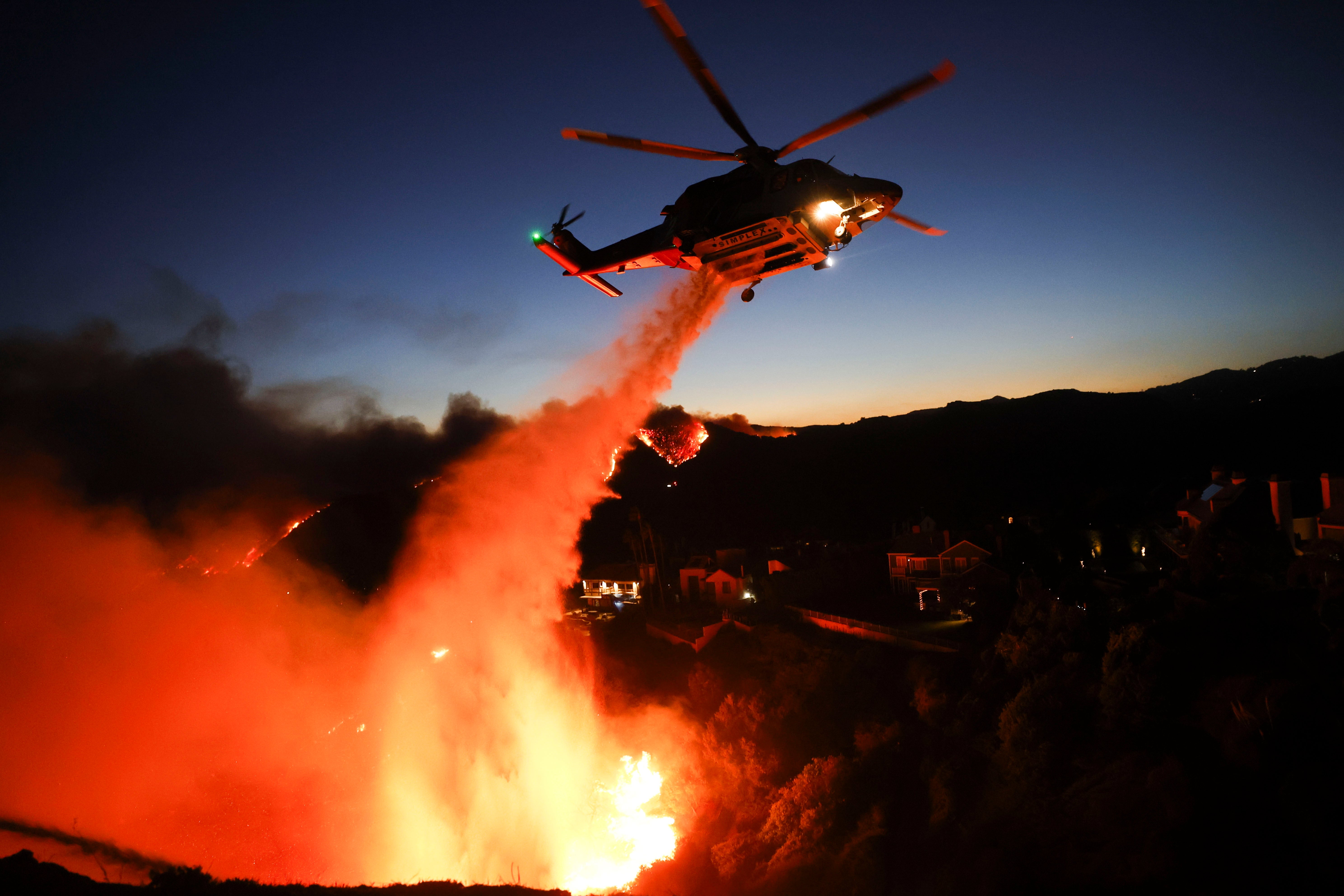 A Los Angeles County firefighting helicopter drops water to battle the Palisades wildfire in Pacific Palisades, a neighborhood known for its beaches and celebrity residents. In a matter of hours, the blaze grew to more than 2,900 acres and prompted roughly 155,000 people to evacuate. Celebrities, including Hailey Bieber, Paris Hilton, and Chris Pratt offered prayers for the traumatized city.