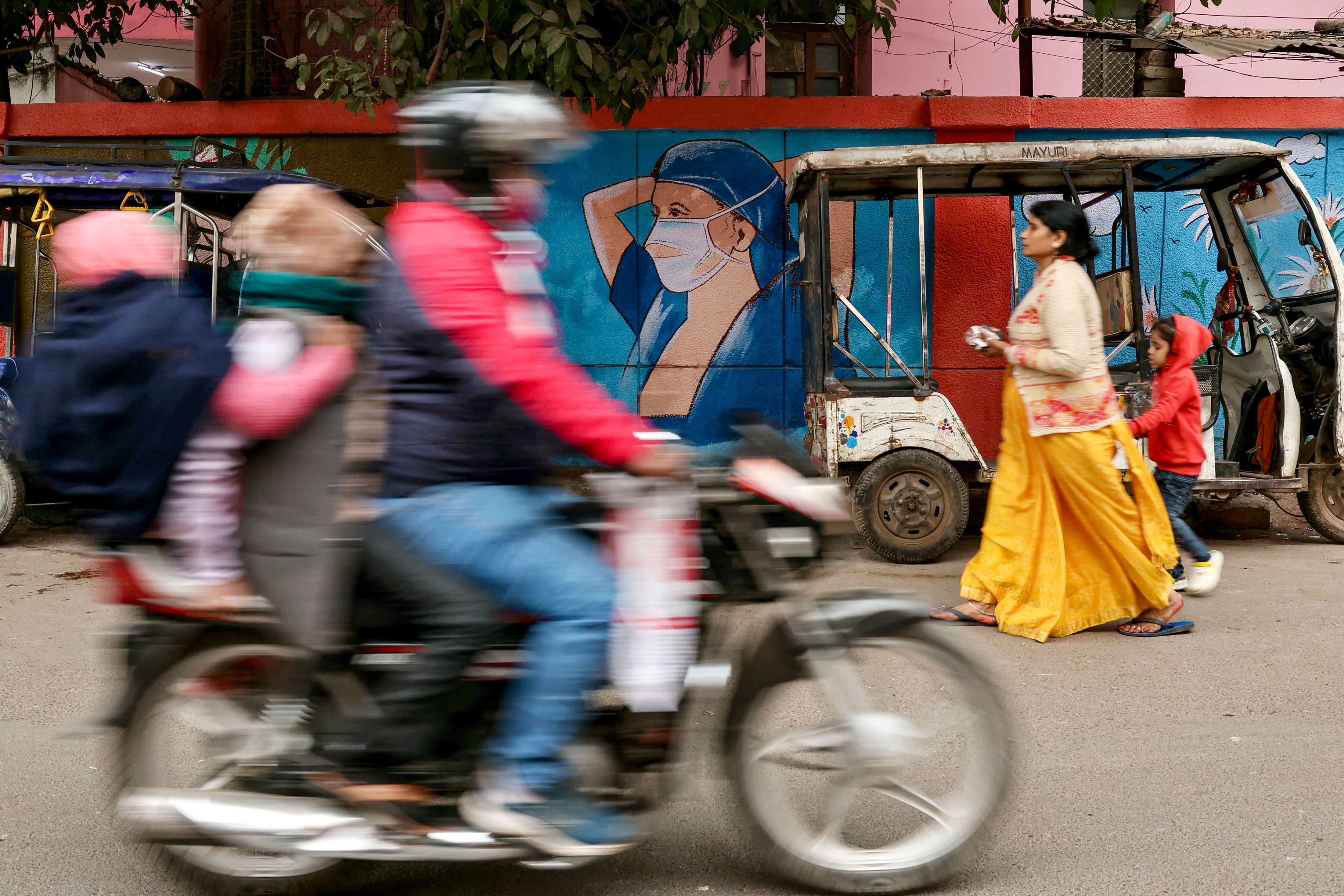 A woman walks past a public health mural in India amid a HMPV outbreak