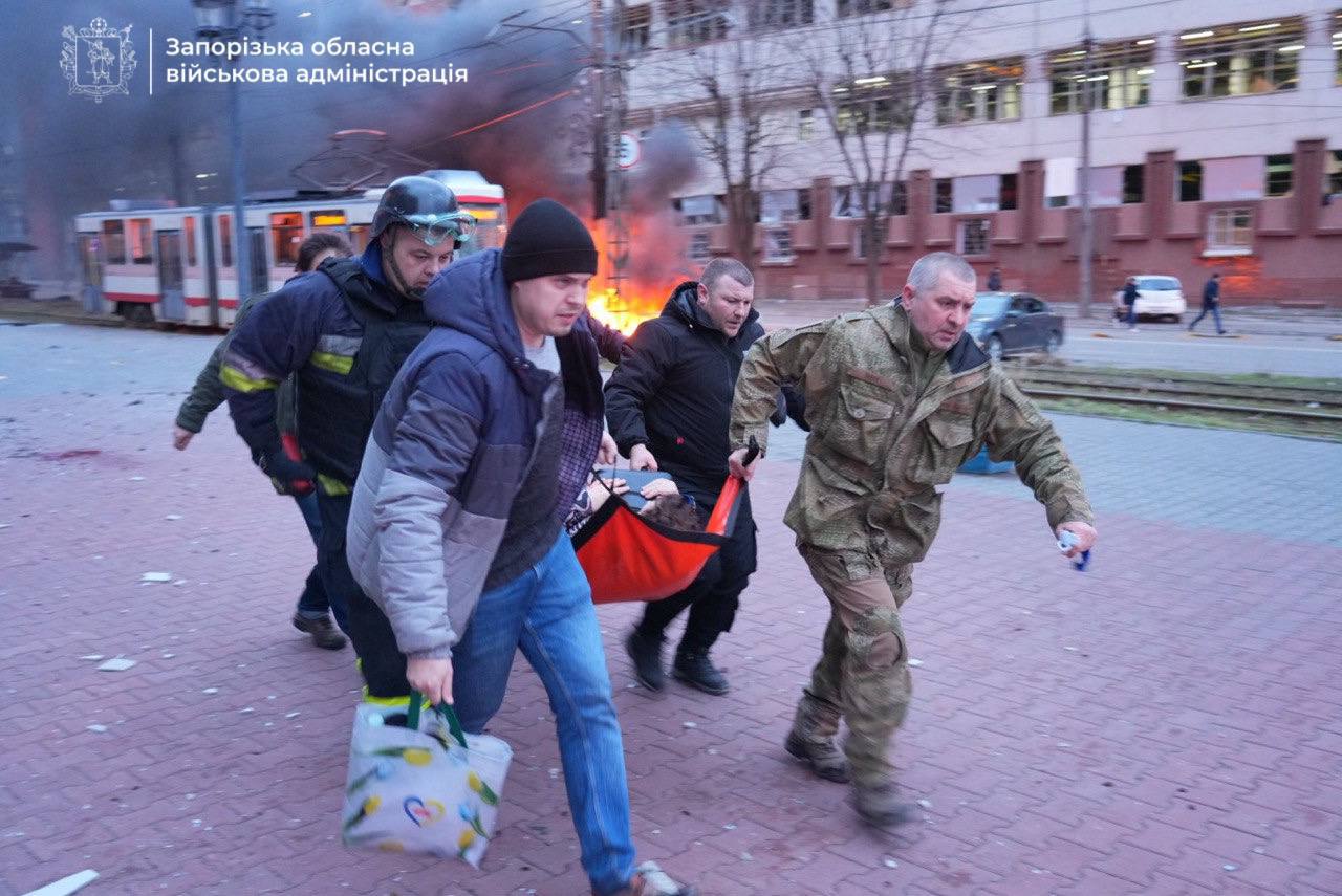 Emergency service workers carry a woman wounded in the Russian strike on Zaporizhzhia