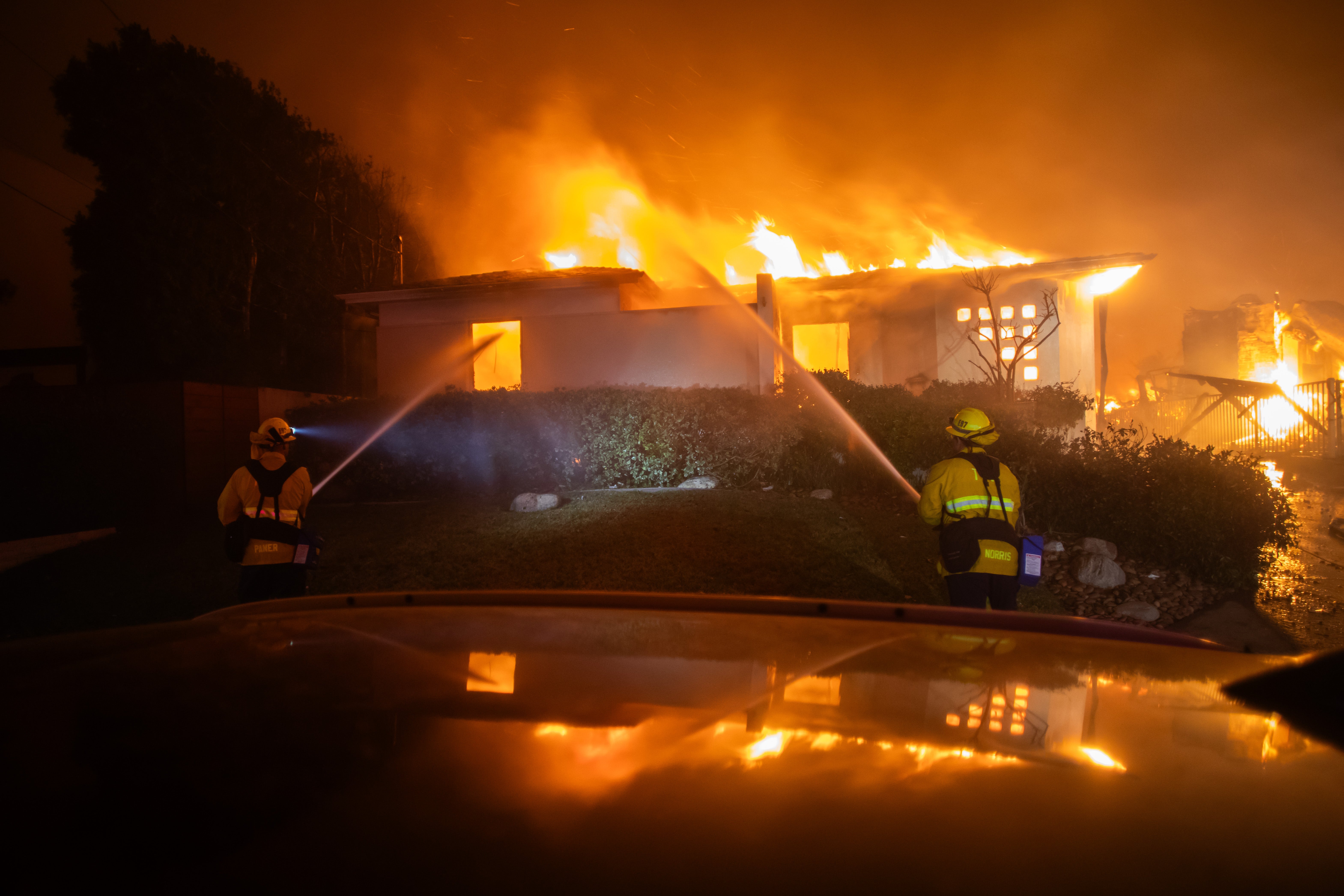 Firefighters fight the flames from the Palisades Fire burning a house during a powerful windstorm Wednesday in the Pacific Palisades neighborhood of Los Angeles, California.