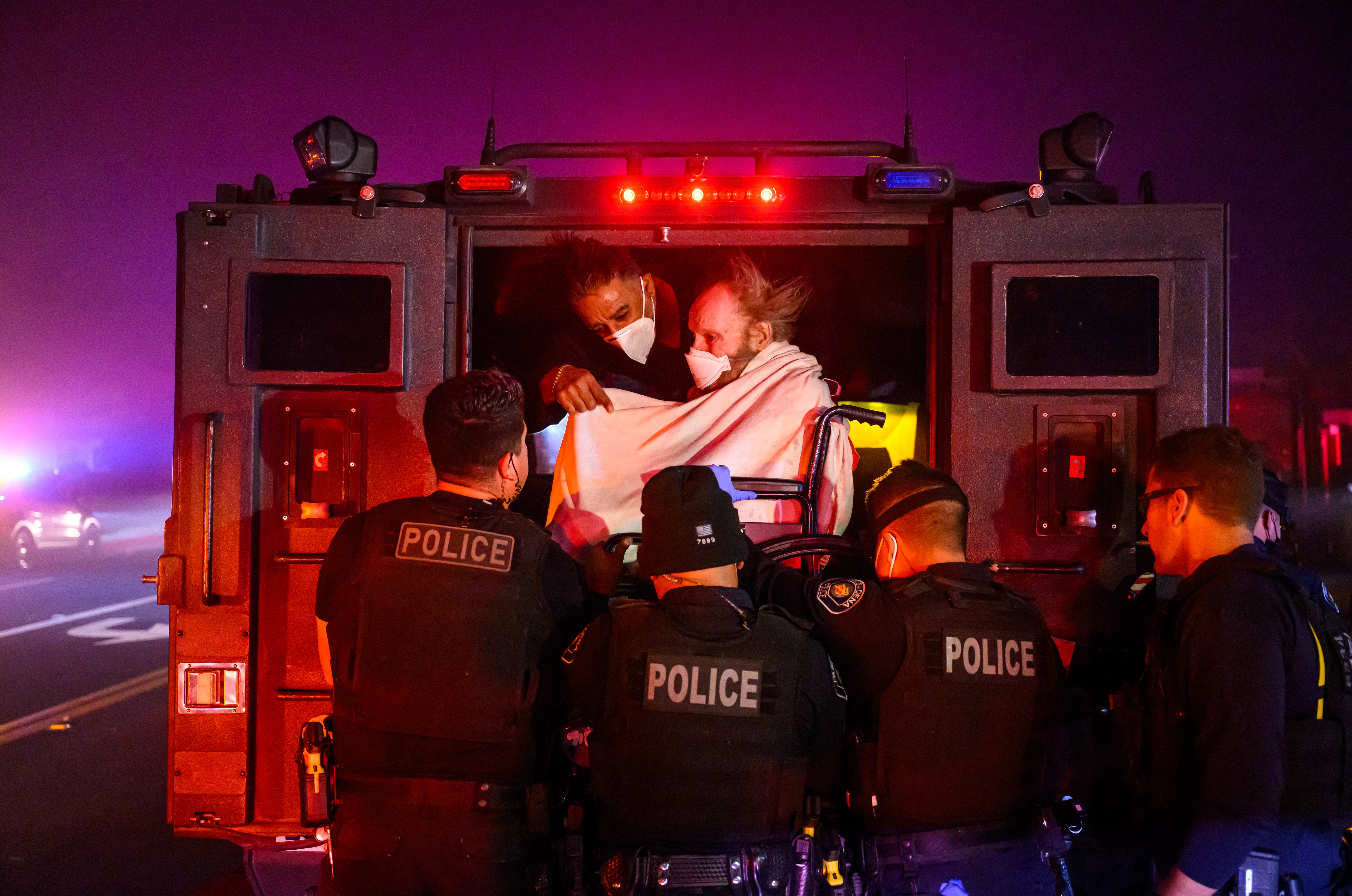 Elderly patients are quickly evacuated into an armored vehicle as embers and flames approach during the Eaton fire in Pasadena, California