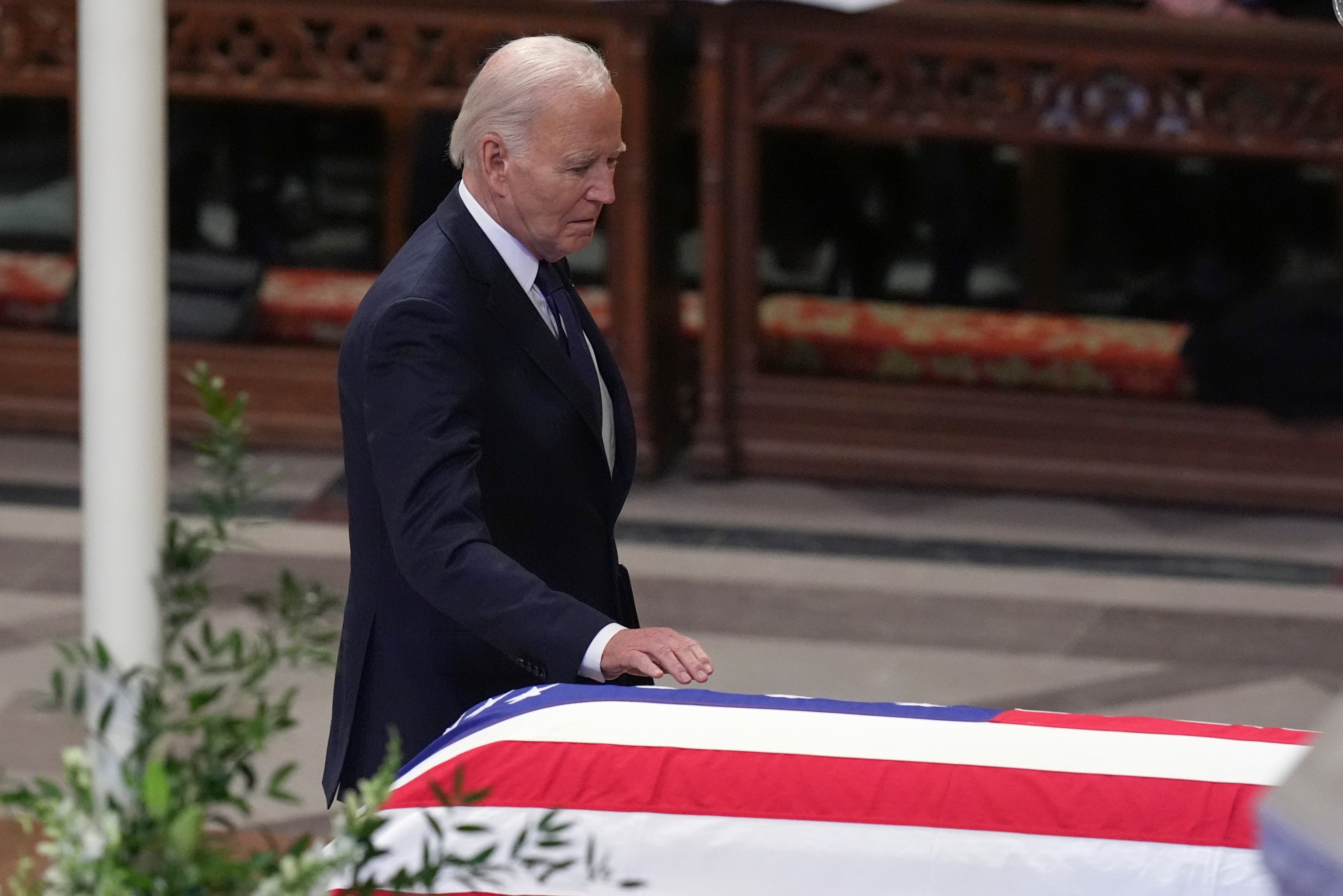 President Joe Biden touches the casket of former President Jimmy Carter during a state funeral service at Washington National Cathedral in Washington, Thursday, Jan. 9, 2025