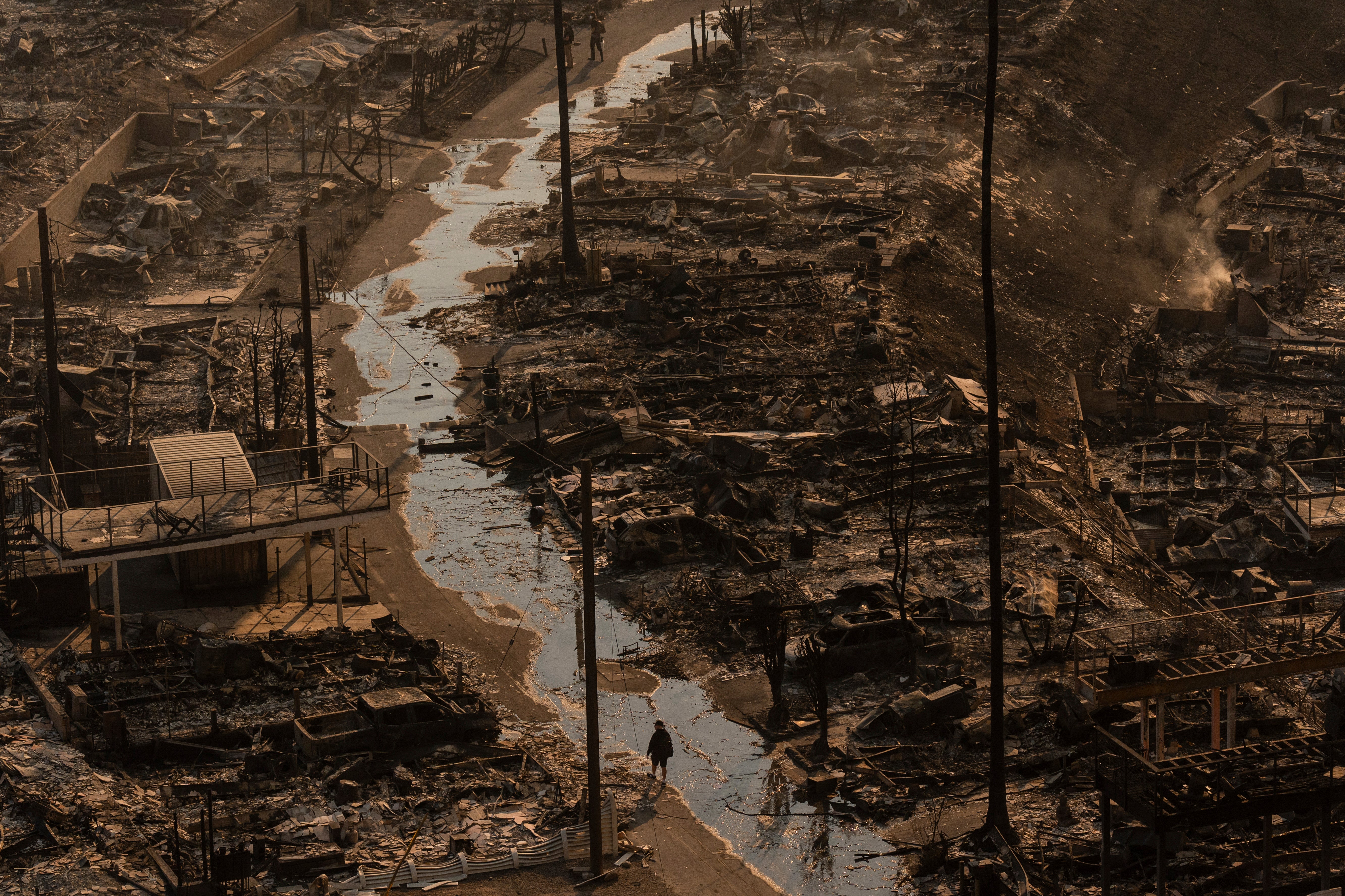 A person walks amid the destruction left behind by the Palisades Fire in the Pacific Palisades neighborhood