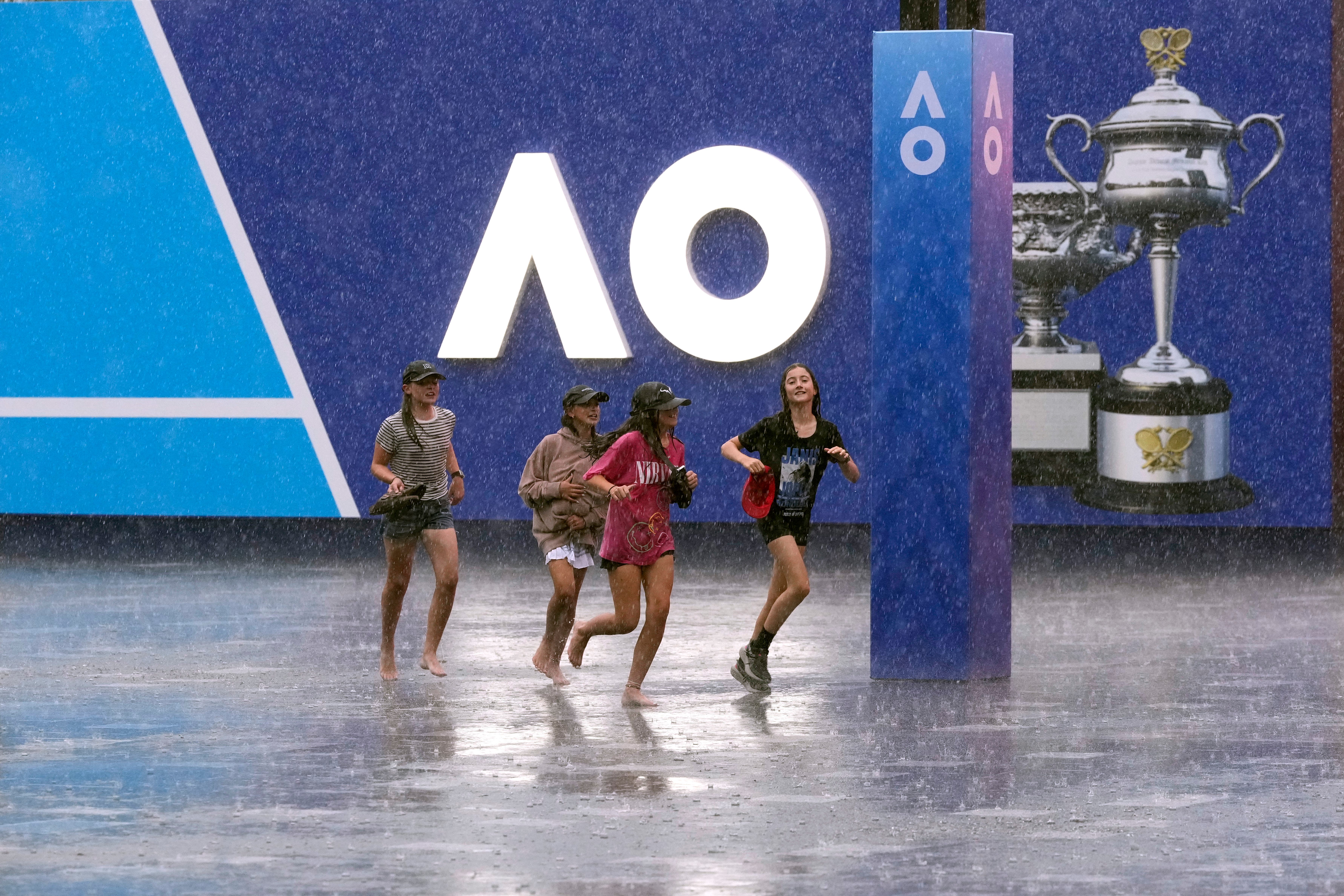 Children run in the rain at Melbourne Park (Manish Swarup/AP)
