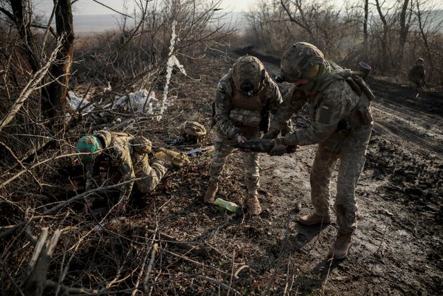 <p>Ukrainian servicemen collect damaged ammunition on the road at the front line near Chasiv Yar town, in Donetsk region</p>