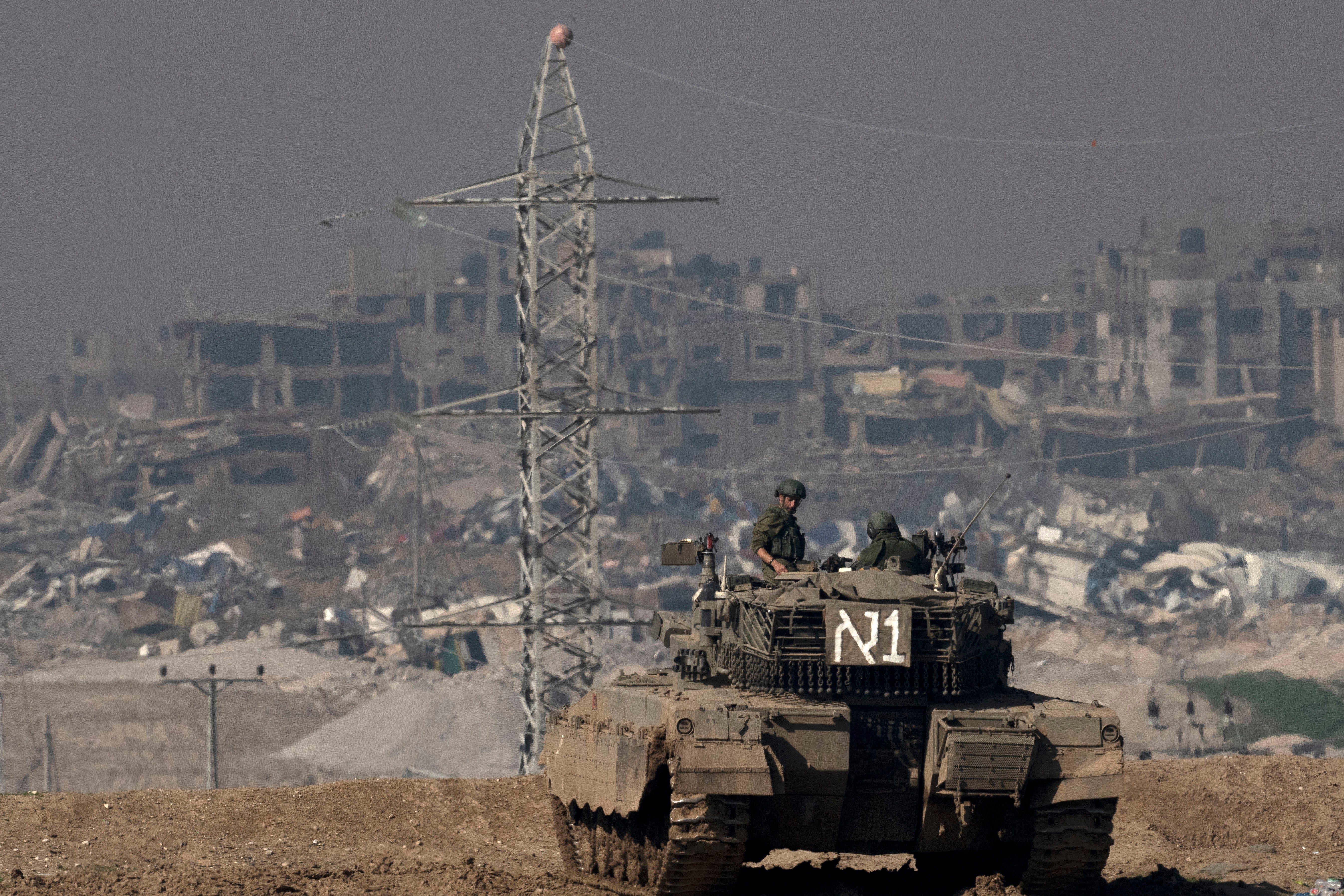 Israeli soldiers overlook the Gaza Strip from a tank, as seen from southern Israel, on Friday