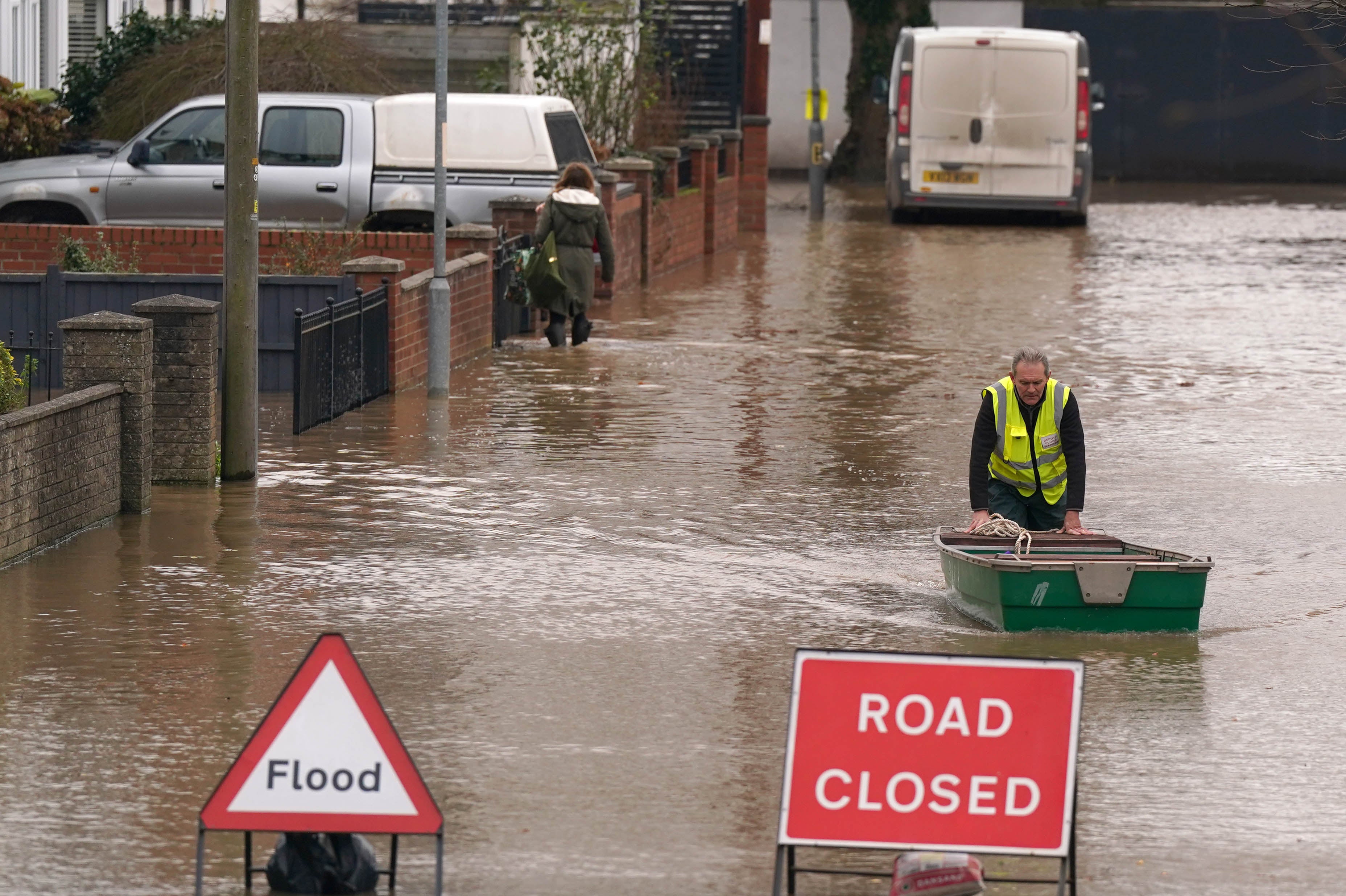 A warden pushes a boat in floodwater following Storm Darragh in December 2024