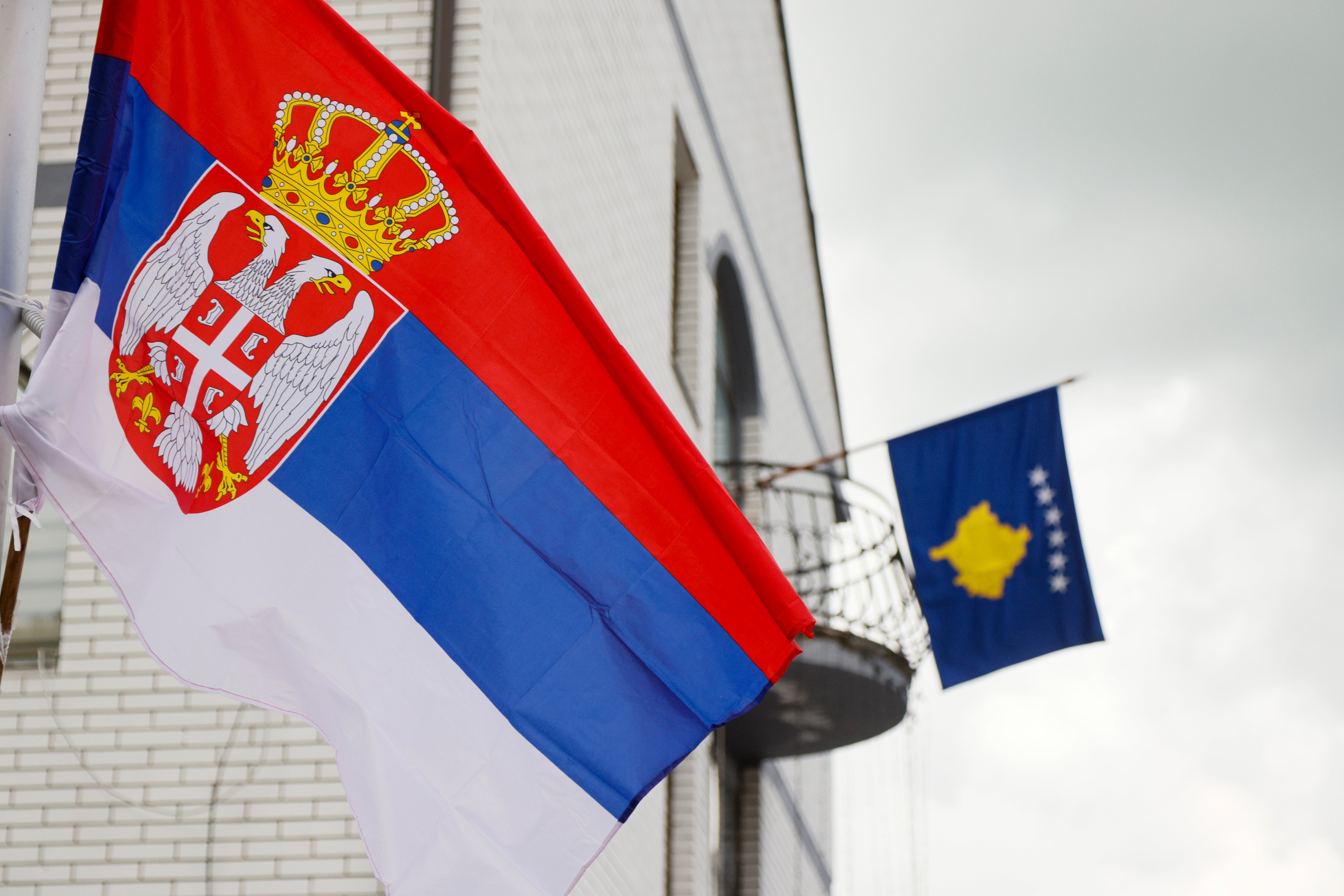 The Serbian flag, left, flies on a lamppost in front of a Kosovo flag on the city hall in the town of Zubin Potok, northern Kosovo, May 31, 2023