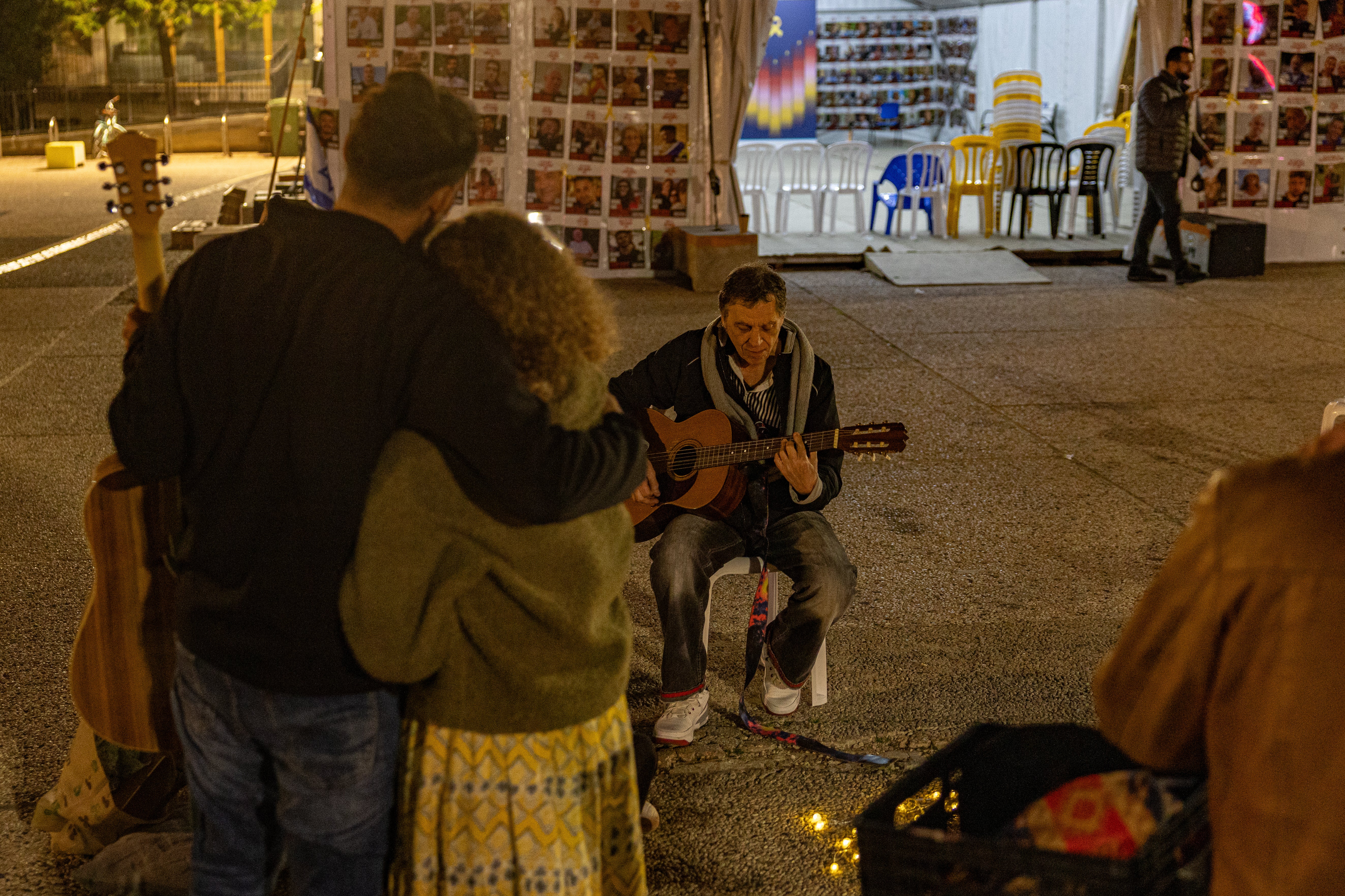 A man plays his guitar in Hostages Square as people watch on