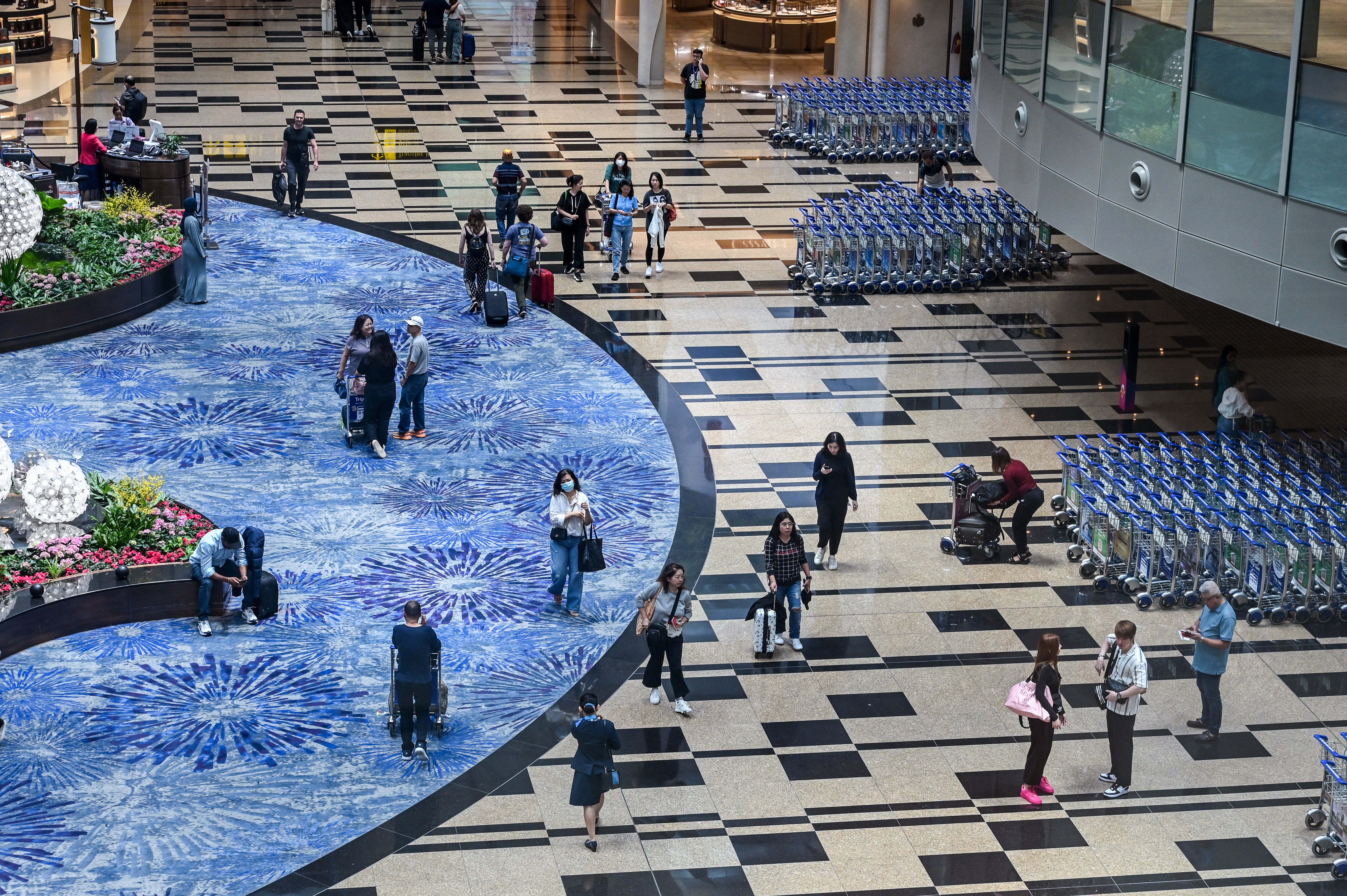 File. Passengers walk through the departure transit hall at Singapore Changi airport
