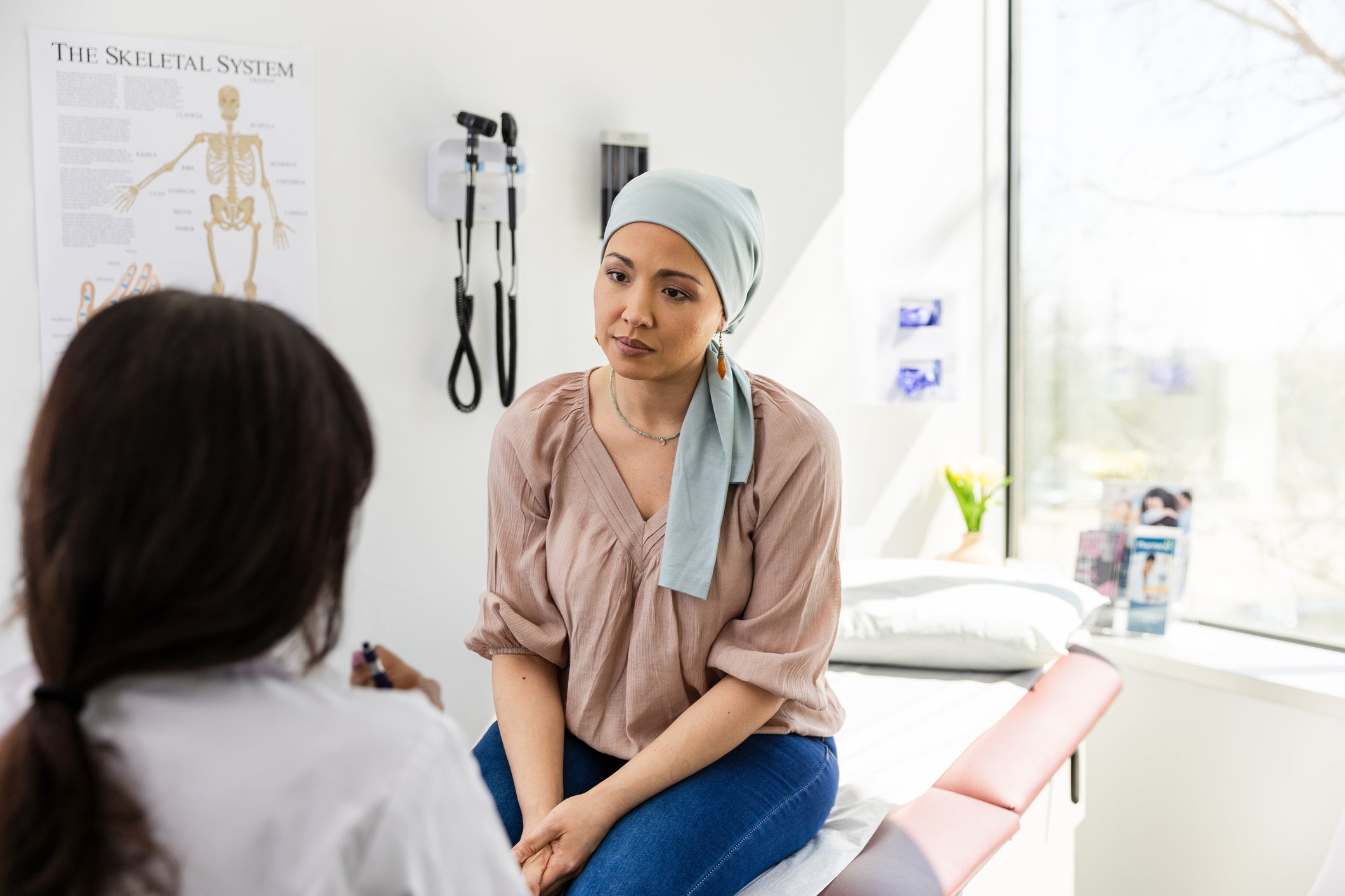 A young woman with cancer listens to her doctor. While the rate of cancer deaths has fallen in recent years, experts warn of ‘alarming’ inequities in cancer deaths