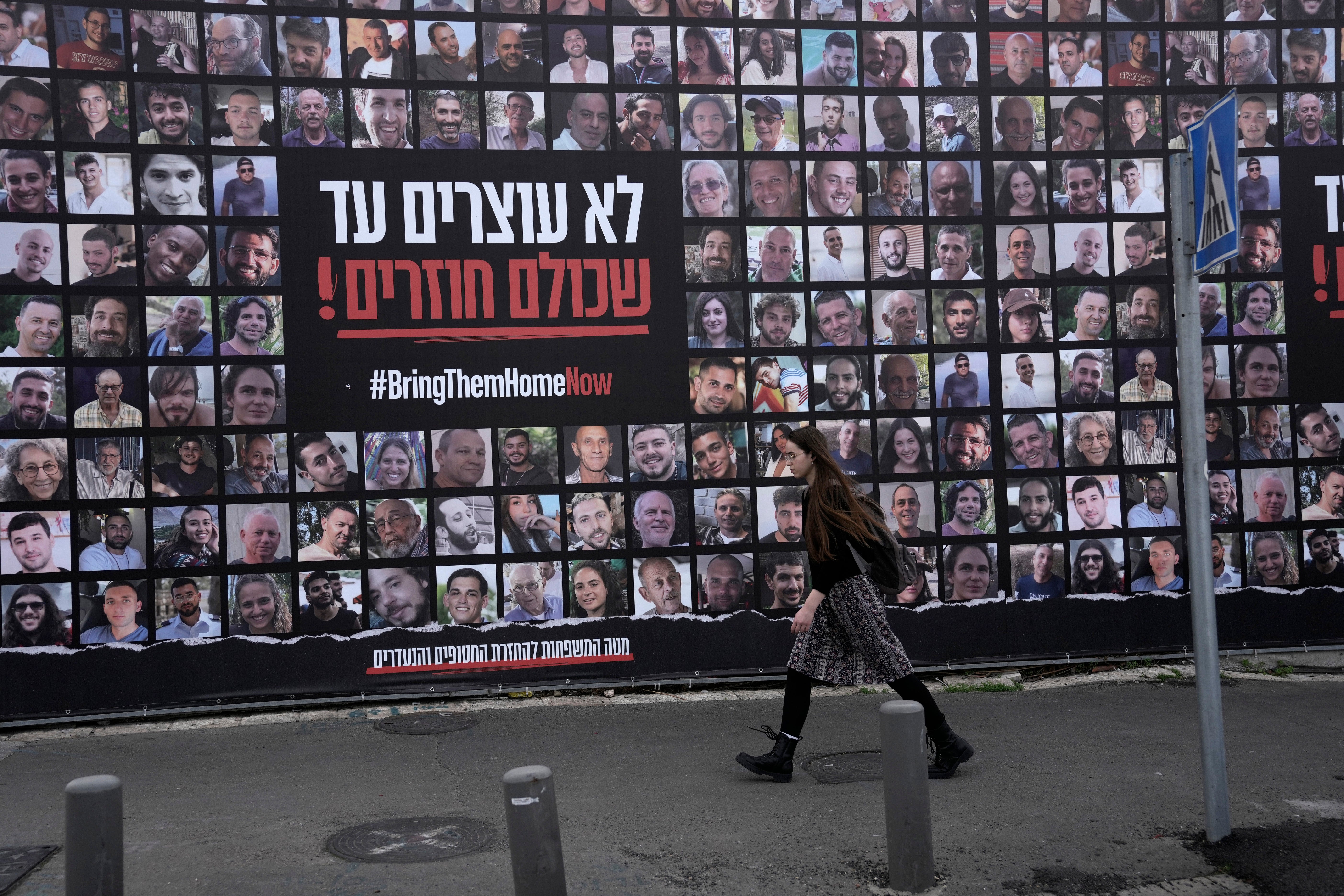 A woman walks past photos of hostages held by Hamas in the Gaza Strip. Many Israelis have celebrated the ceasefire, with others describing it as capitulation to Hamas