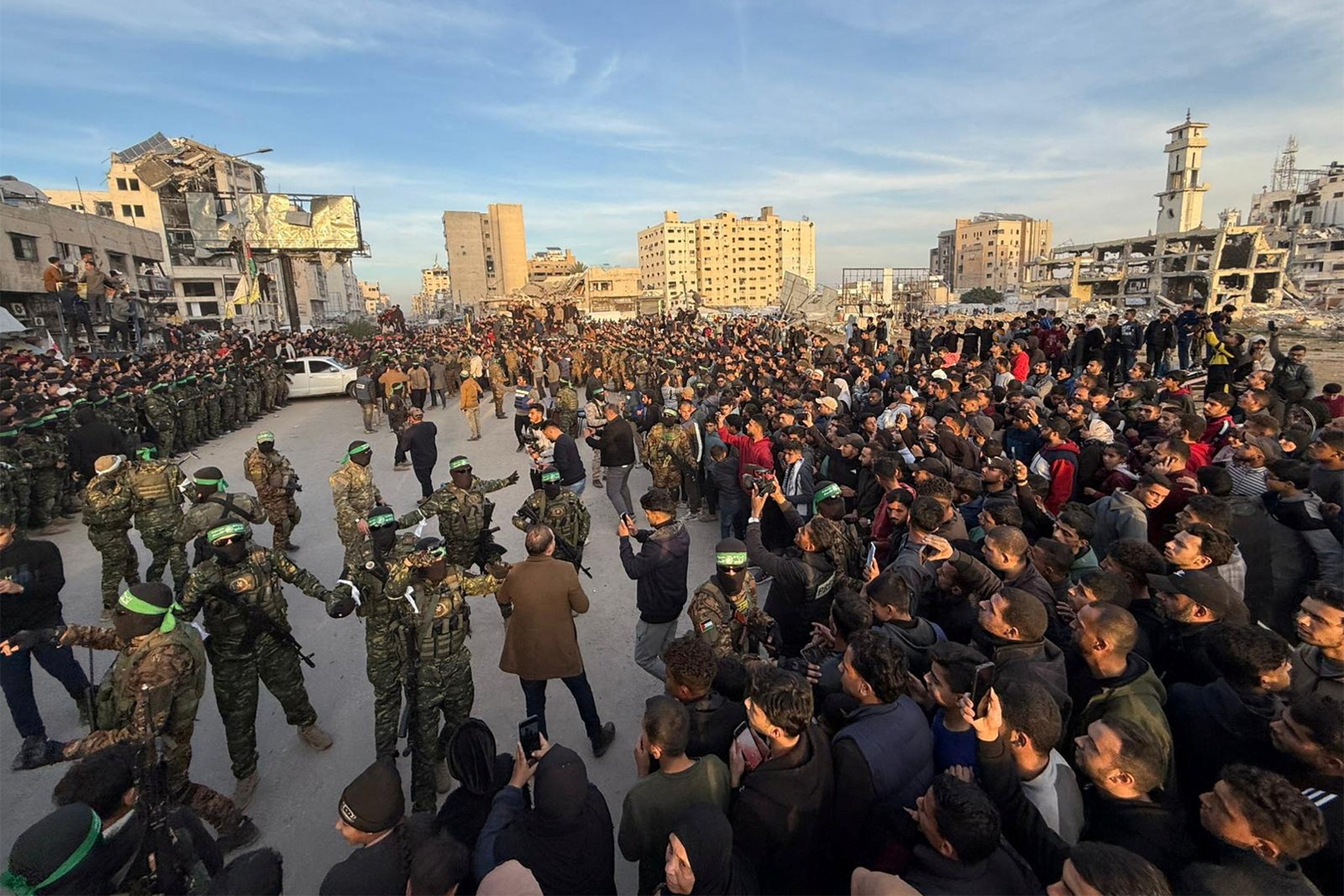 Hamas militants keep guard as people gather in Gaza City on Sunday before the release of hostages kidnapped during the 7 October 2023, attack