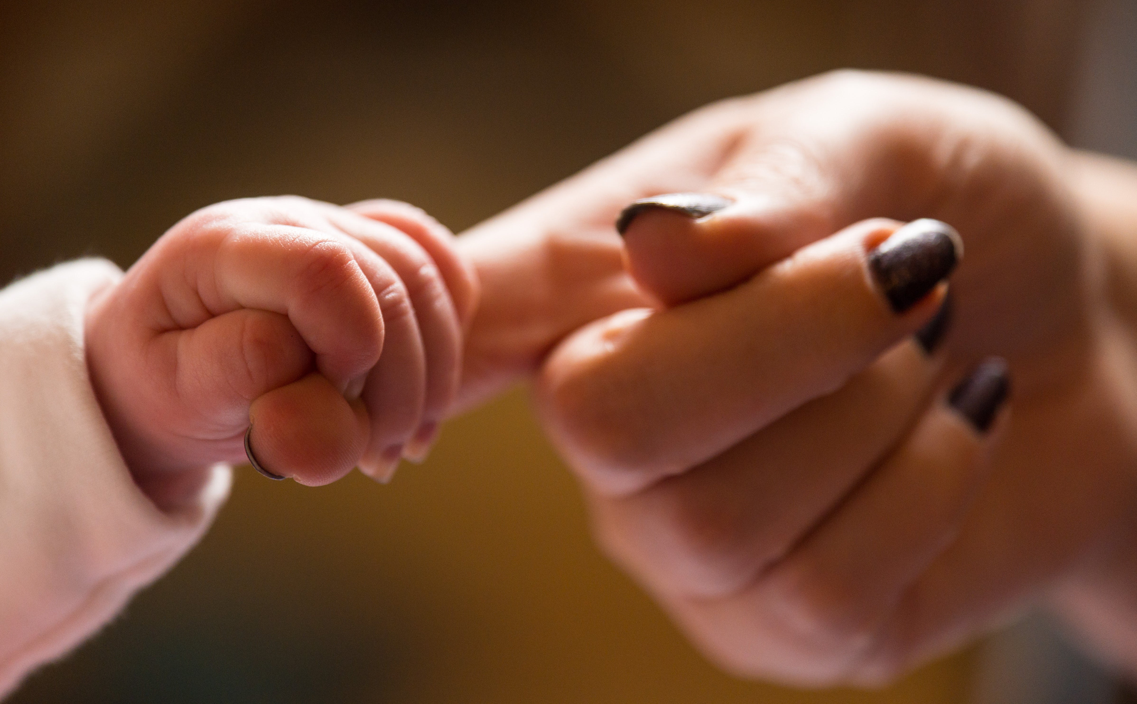 A new baby holding the finger of its mother (Dominic Lipinski/PA)