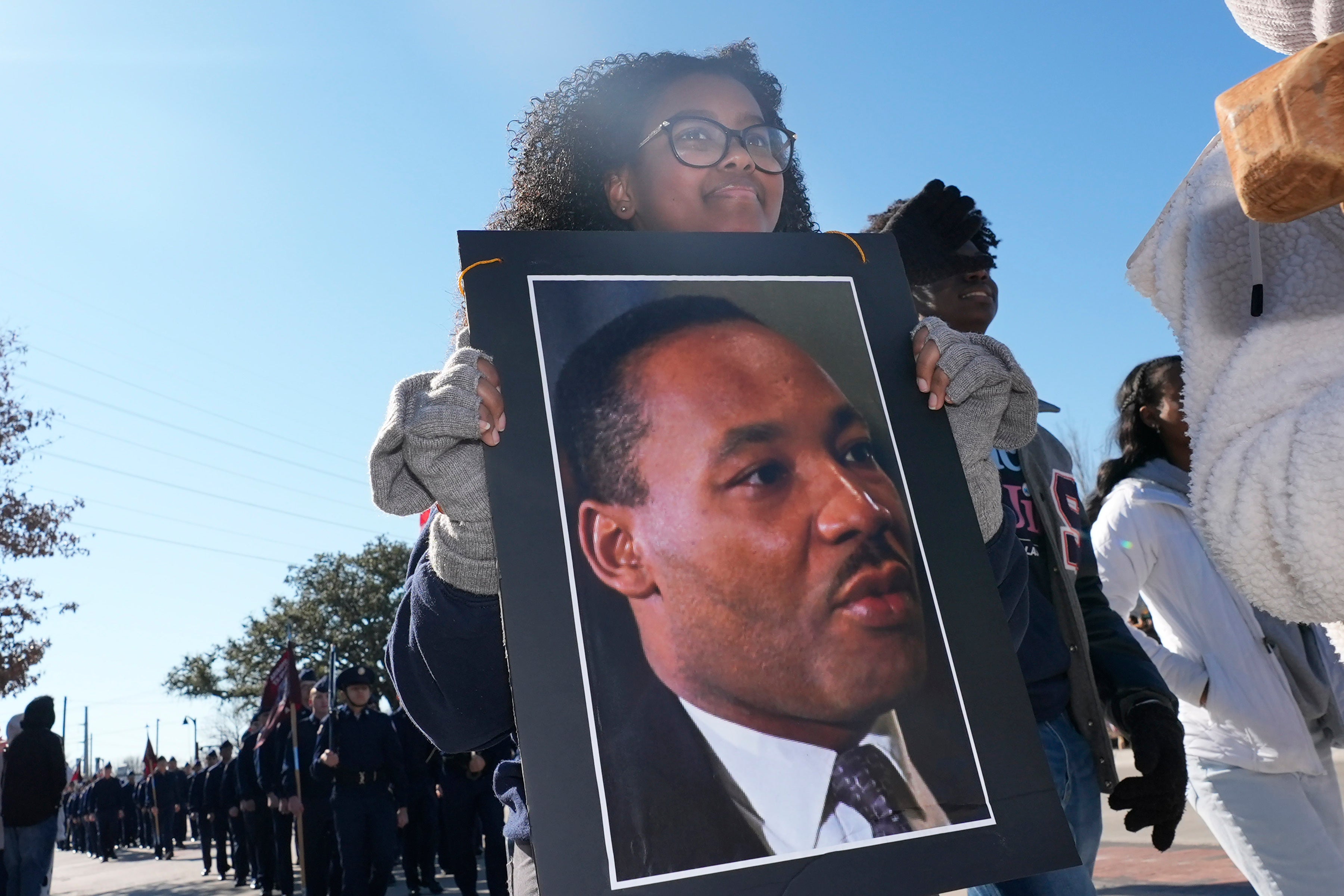 <p>Garland High School senior Saron Lias carries a poster of Dr. Martin Luther King Jr. while marching in the 36th annual MLK Day Parade in Garland, Texas.</p>