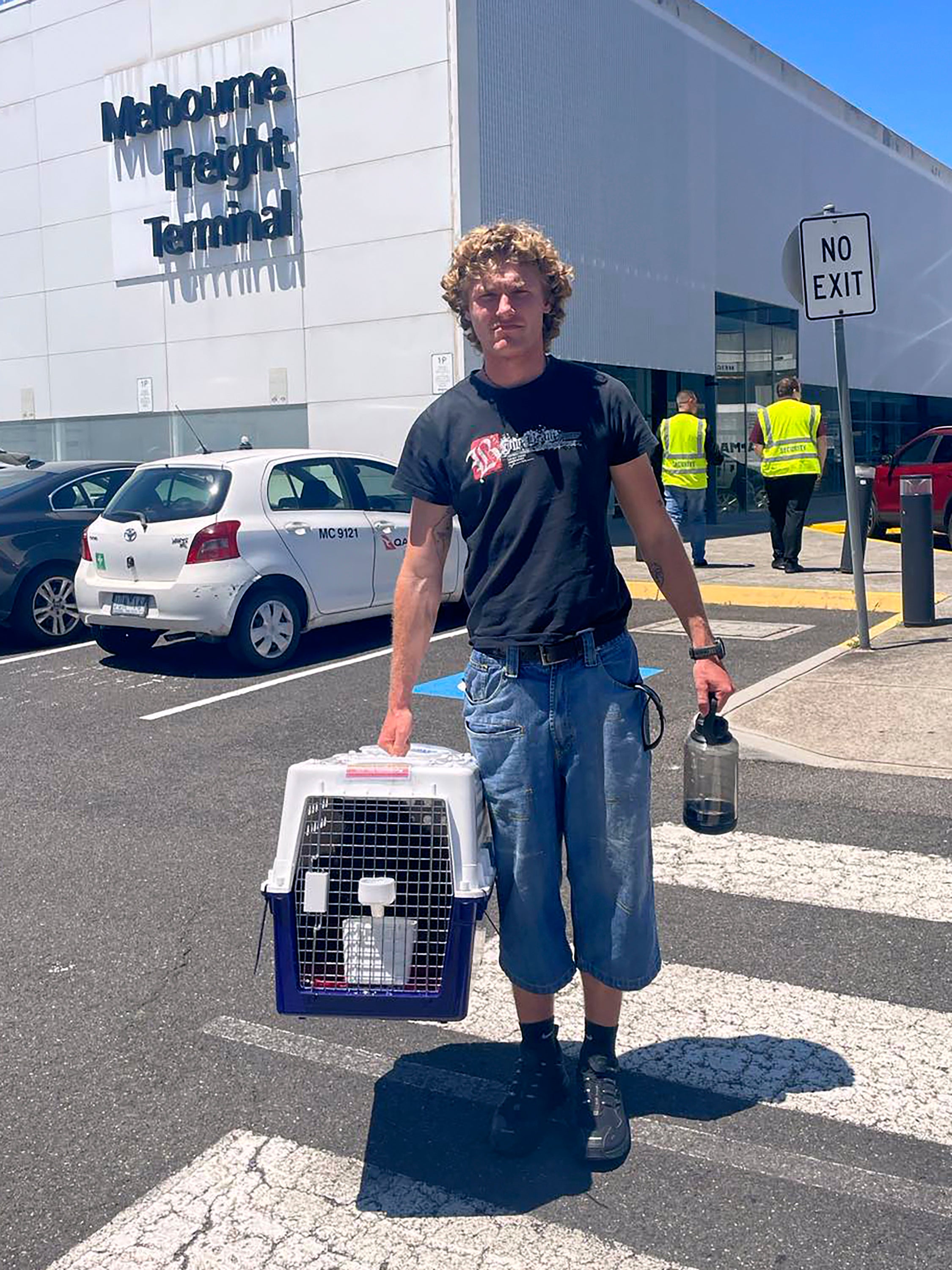 Jackson Brow holds their cat, Mittens, in a cat carrier at Melbourne Airport