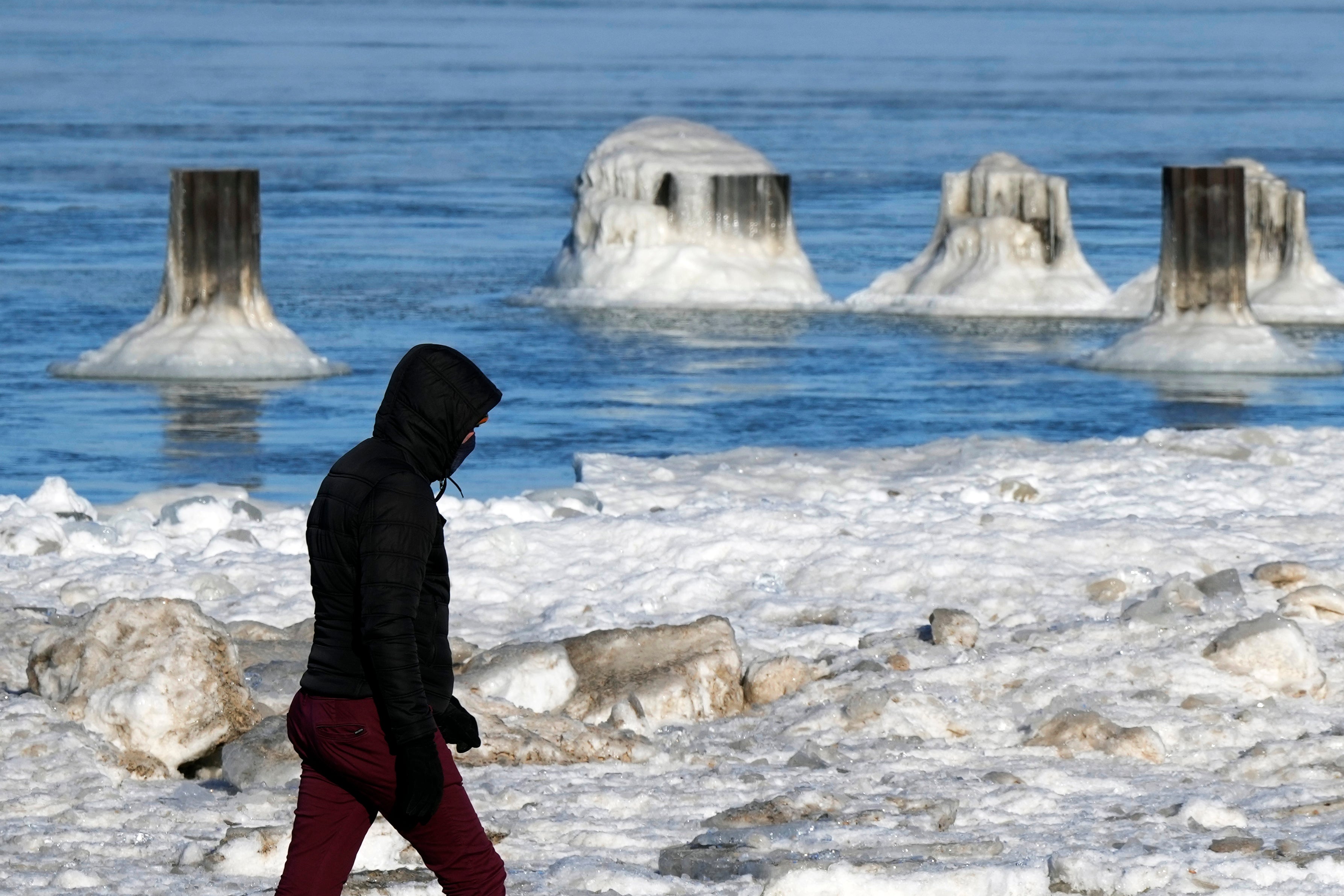 A man walks along the shore of snow-covered Lake Michigan during a cold day in Chicago [stock image]