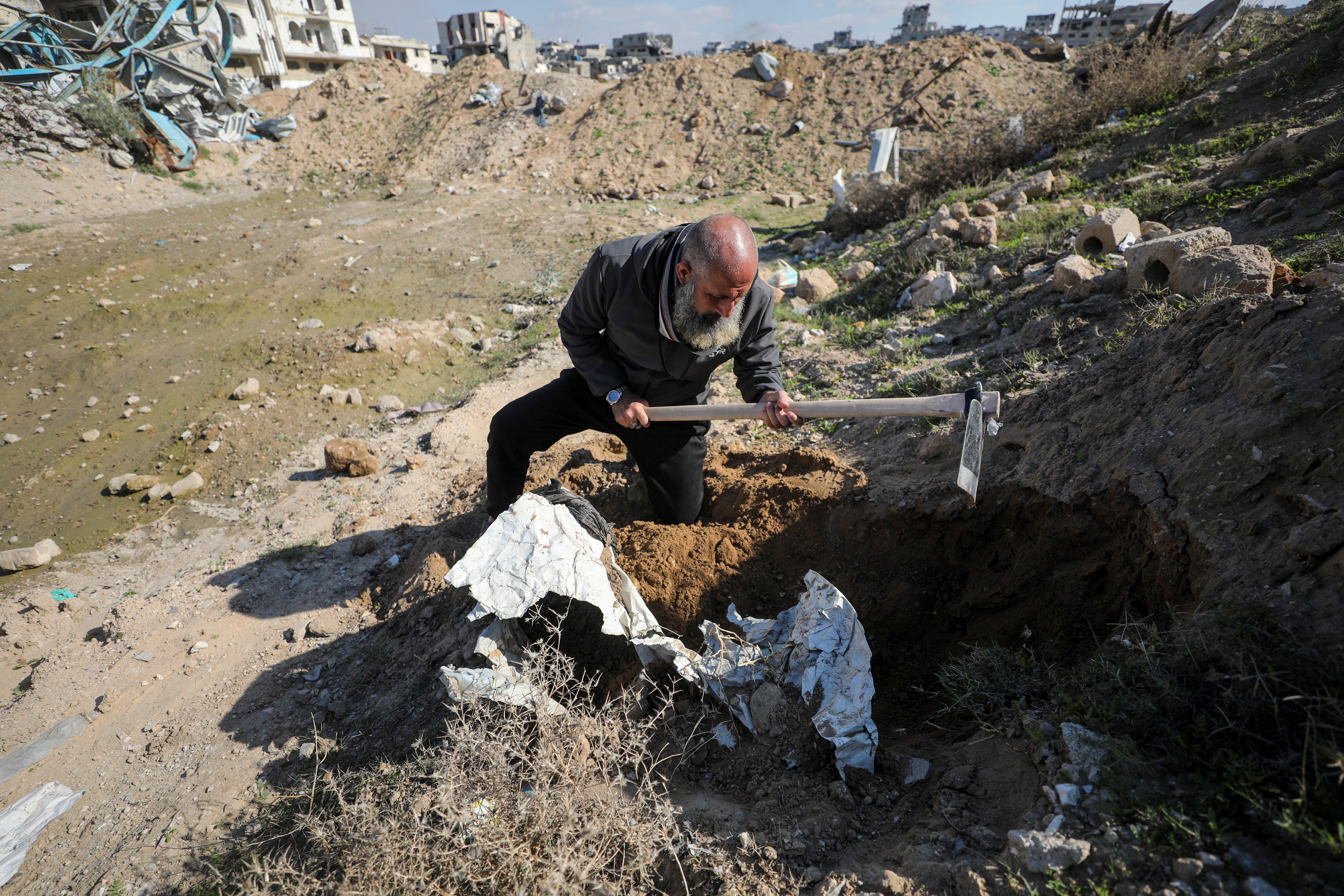 Palestinian man Atef Jundiya searches for the graves and bodies of his father, brother, and brother-in-law
