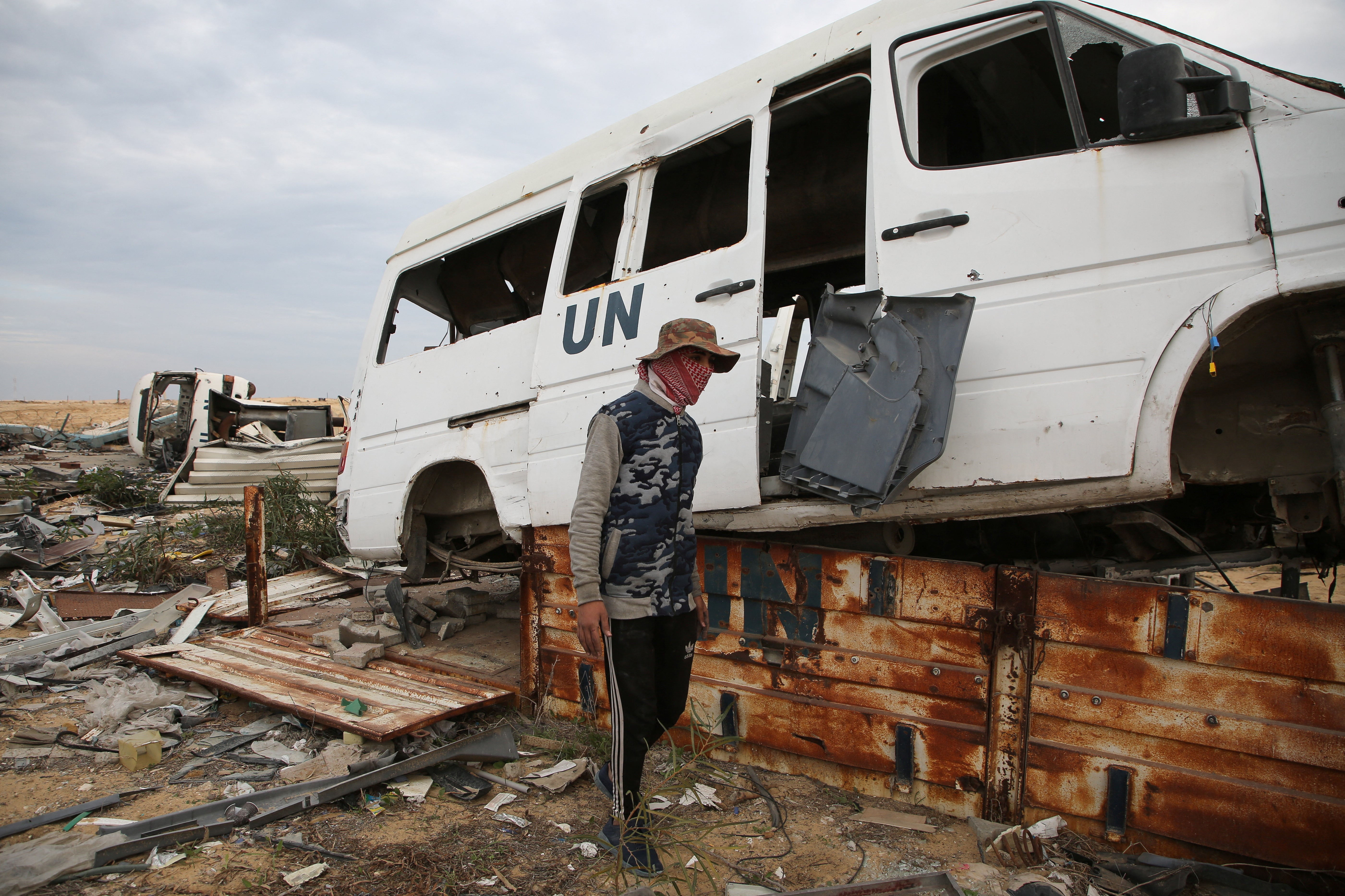 A Palestinian walks next to a UN vehicle damaged during the Israeli offensive