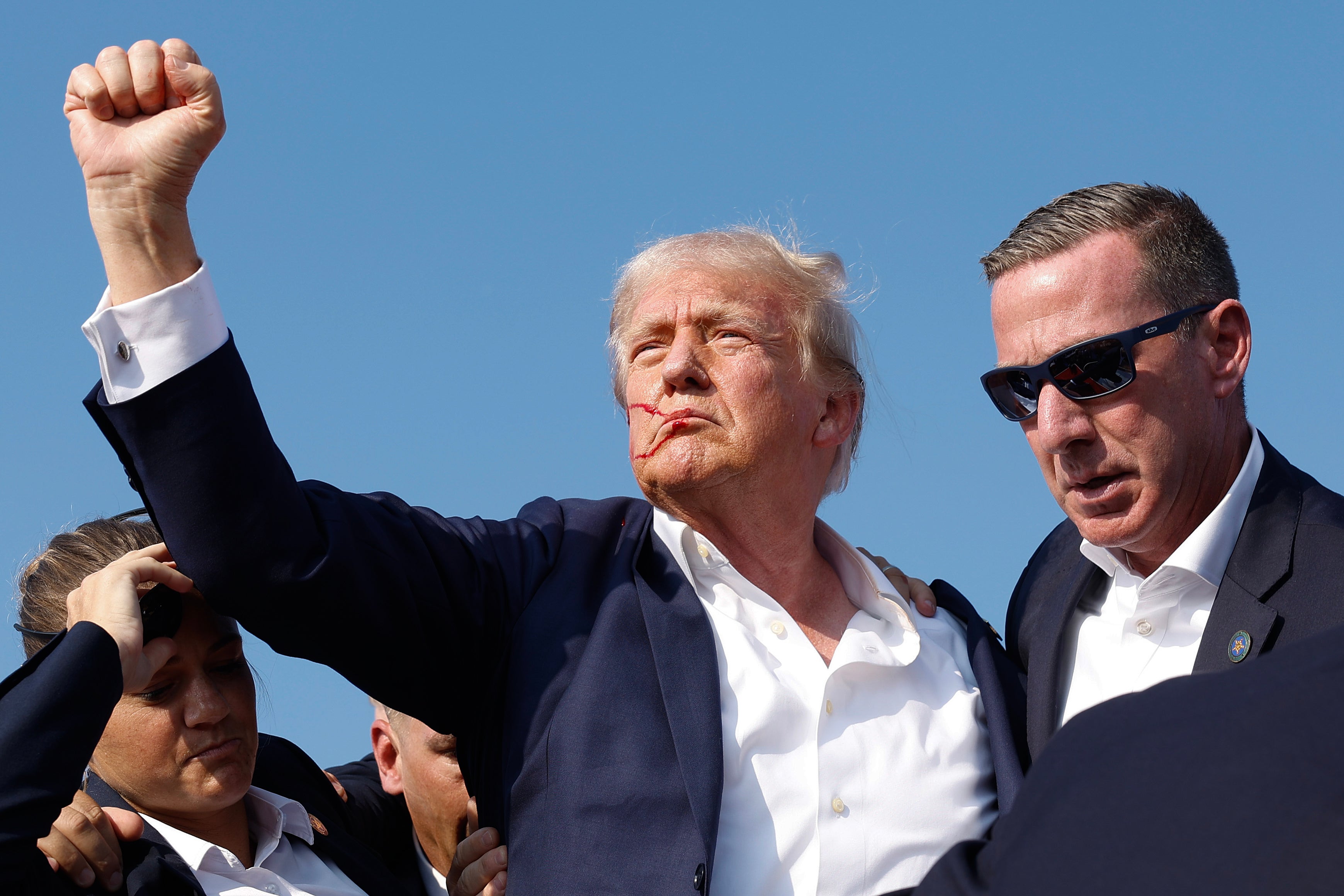 Donald Trump pumps his fist as he is rushed offstage during a rally on July 13, 2024 in Butler, Pennsylvania. Sean Curran, to the right, will be the next director of the Secret Service