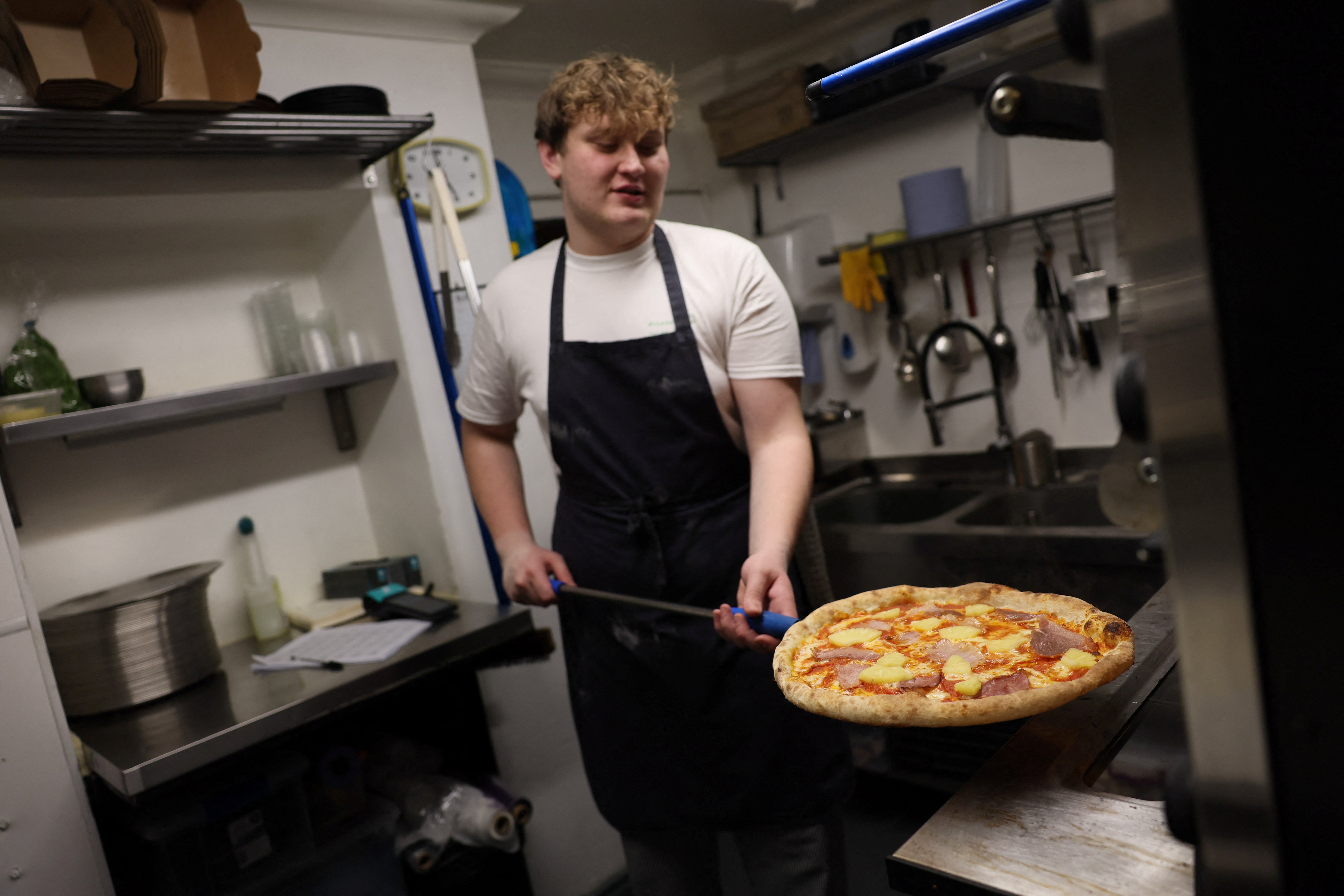 Chef Oliver Bardwell prepares a Hawaiian, ham, and pineapple-topped pizza at Lupa Pizza restaurant in Norwich