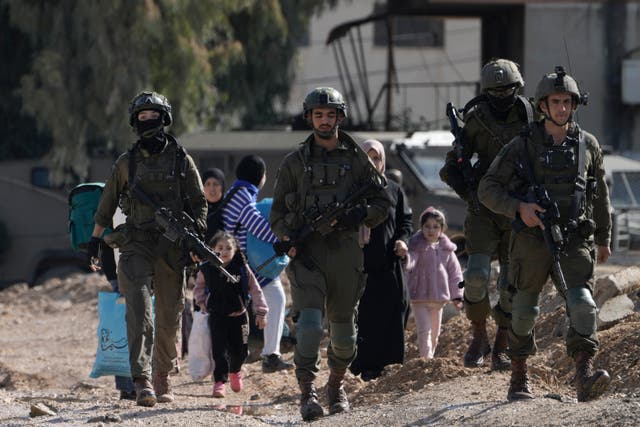 <p>IDF soldiers walk ahead of Palestinians displaced by an Israeli military operation and evacuating from the Jenin refugee camp in the West Bank on Thursday 23 January 2025 </p>