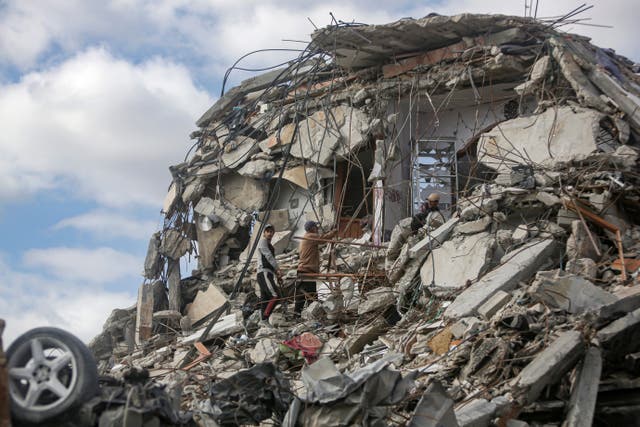 <p>Displaced Palestinians inspect the ruins of their home, which was destroyed in the Israeli bombardment of the Gaza Strip</p>