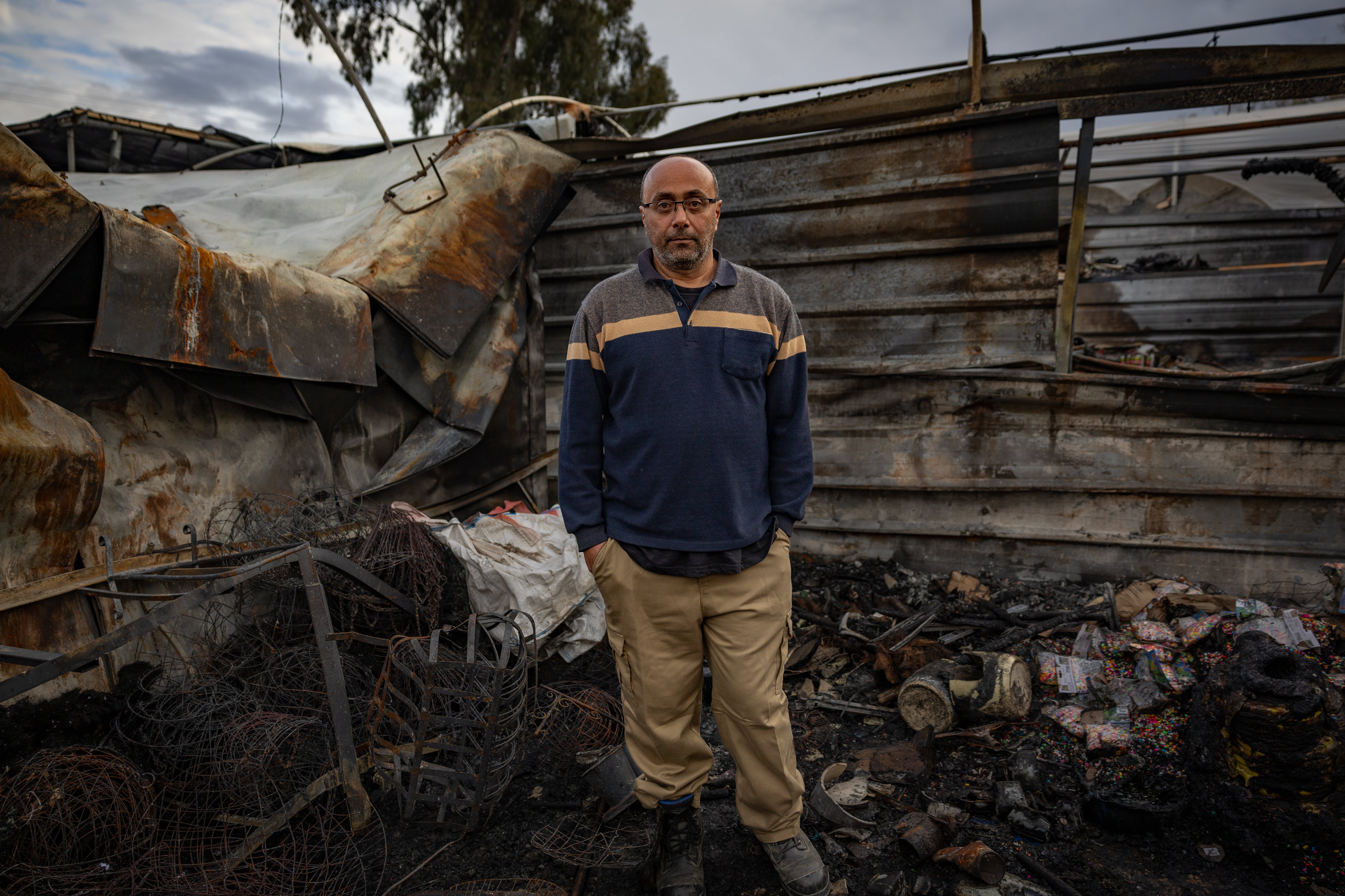 Loay Taym, the mayor of Funduq, stands in the remains of a garden centre torched by Israeli settlers