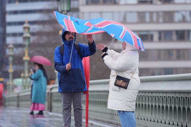 People walking in the wind and rain on Westminster Bridge in London on Sunday (Yui Mok/PA)