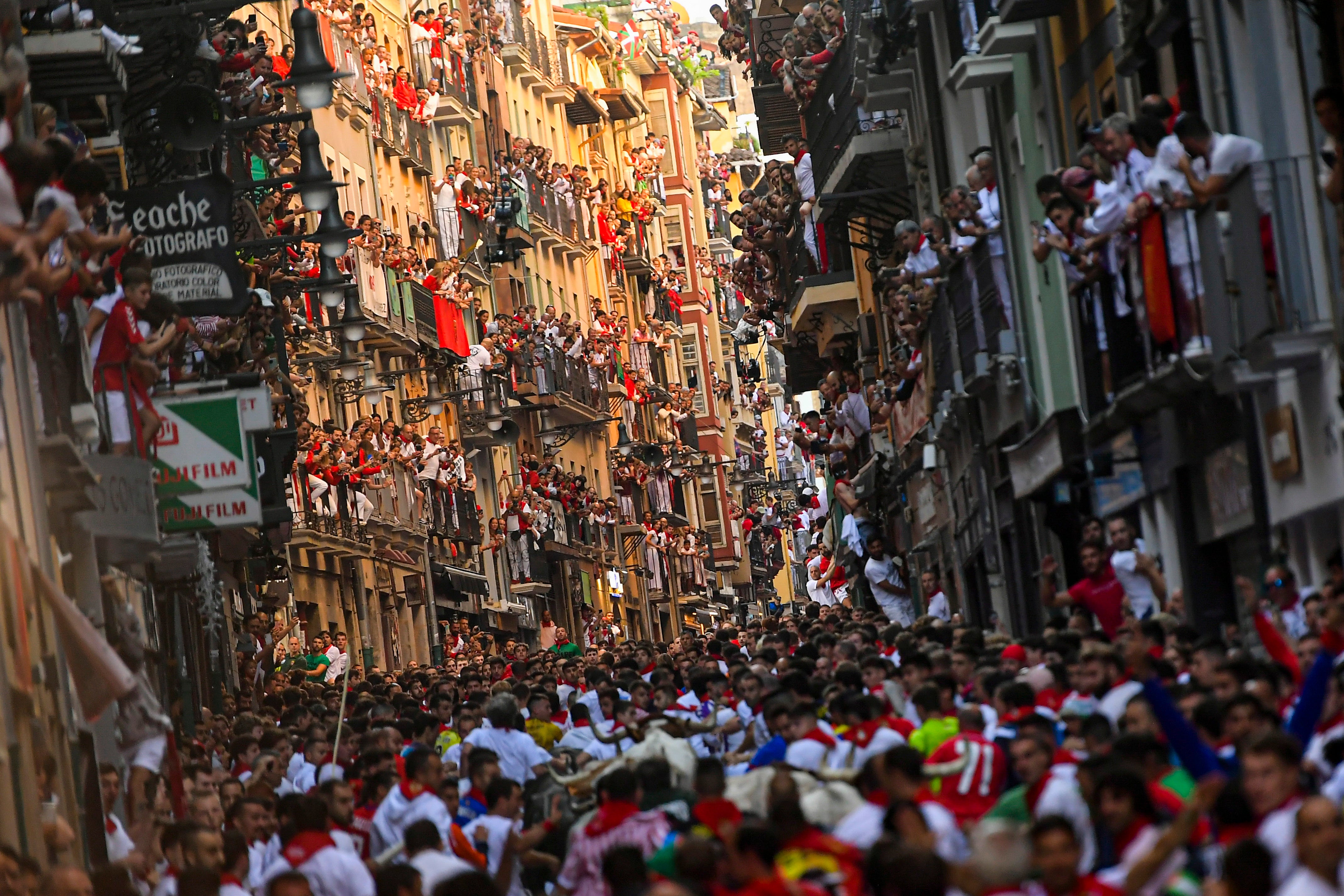 People, mostly tourists, look on from balconies at the running of the bulls during the San Fermín fiestas in Pamplona, Spain